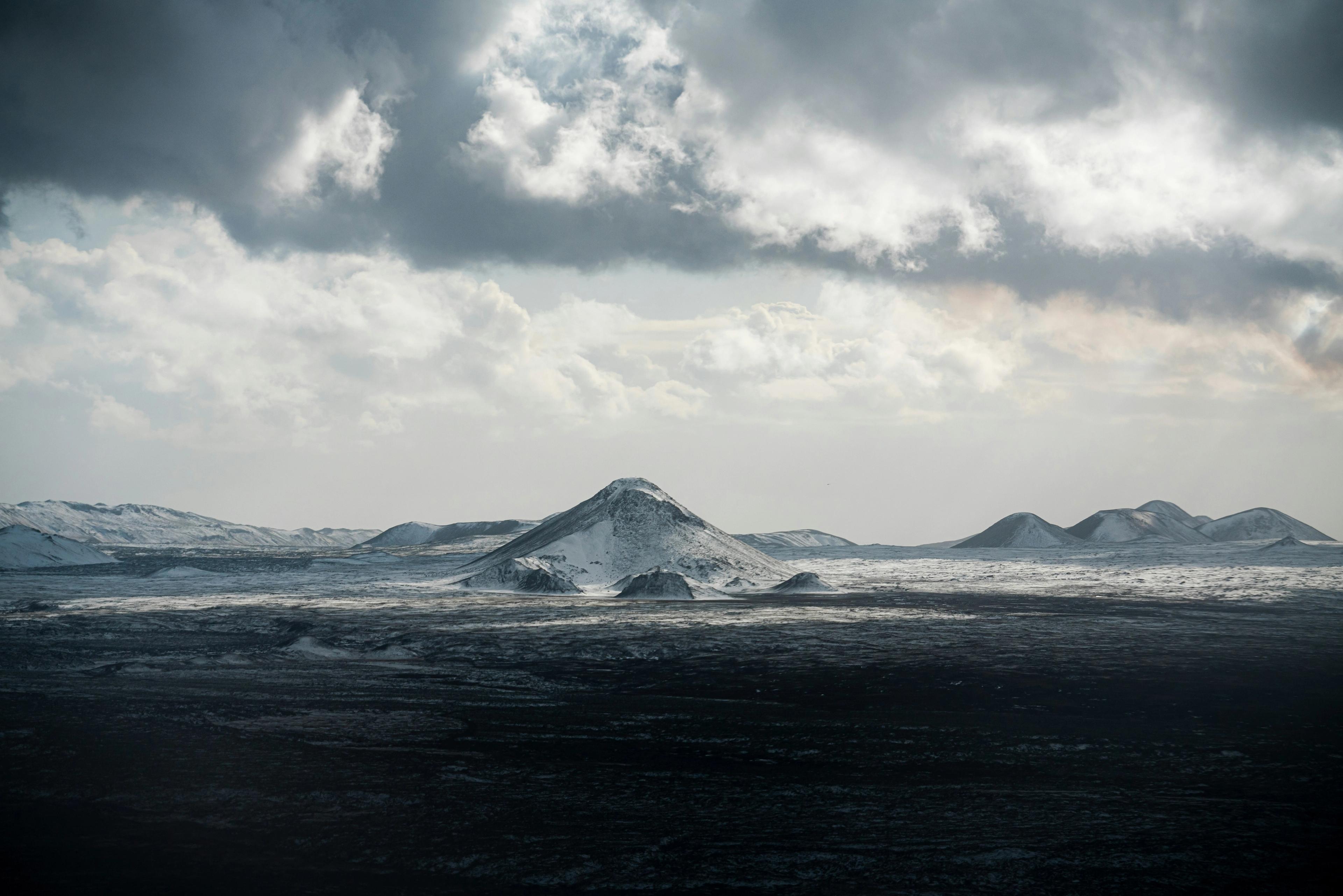 a snowy mountain range with a cloudy sky in the background .