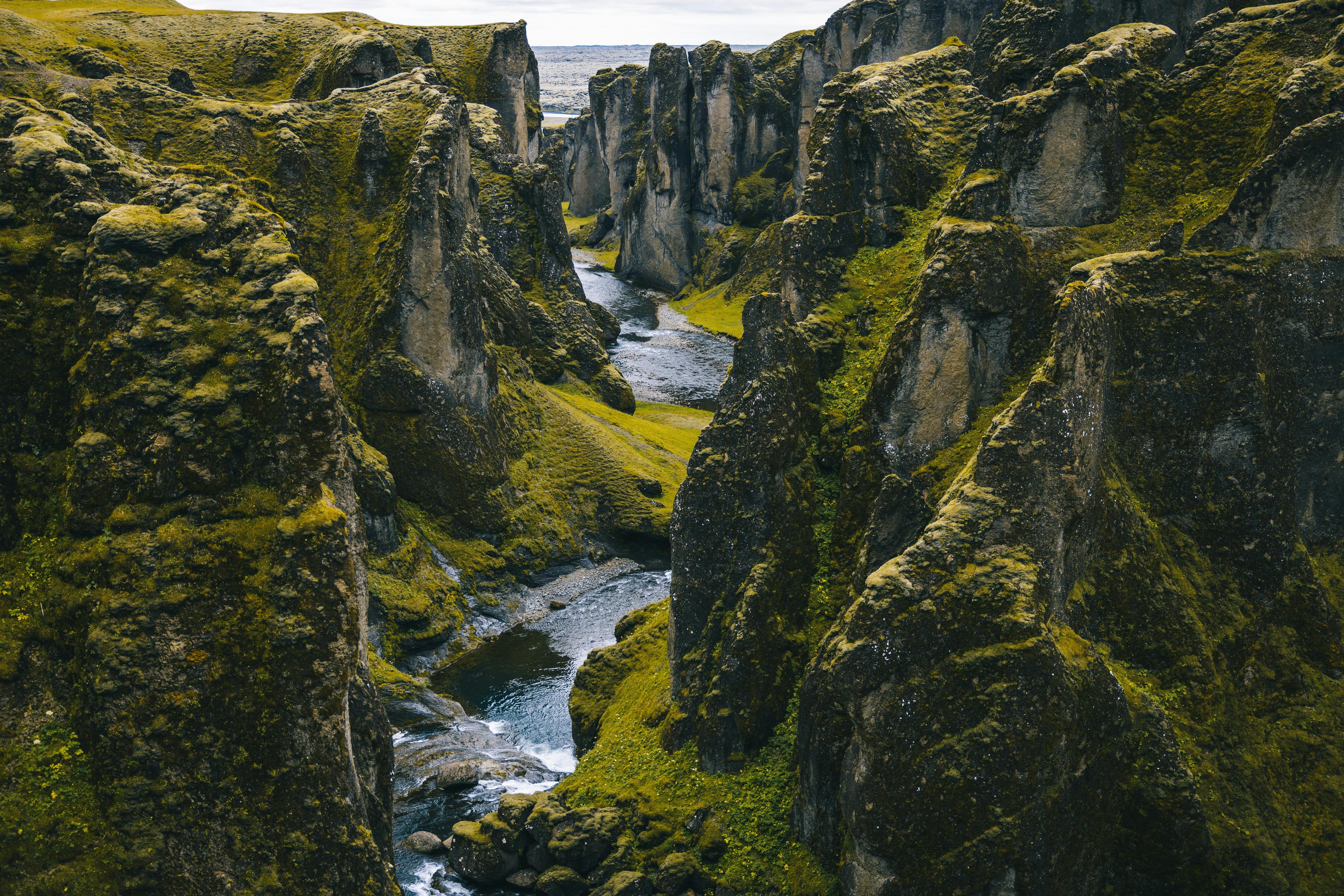 Aerial view of a sinuous river winding through a rugged landscape covered in green moss.
