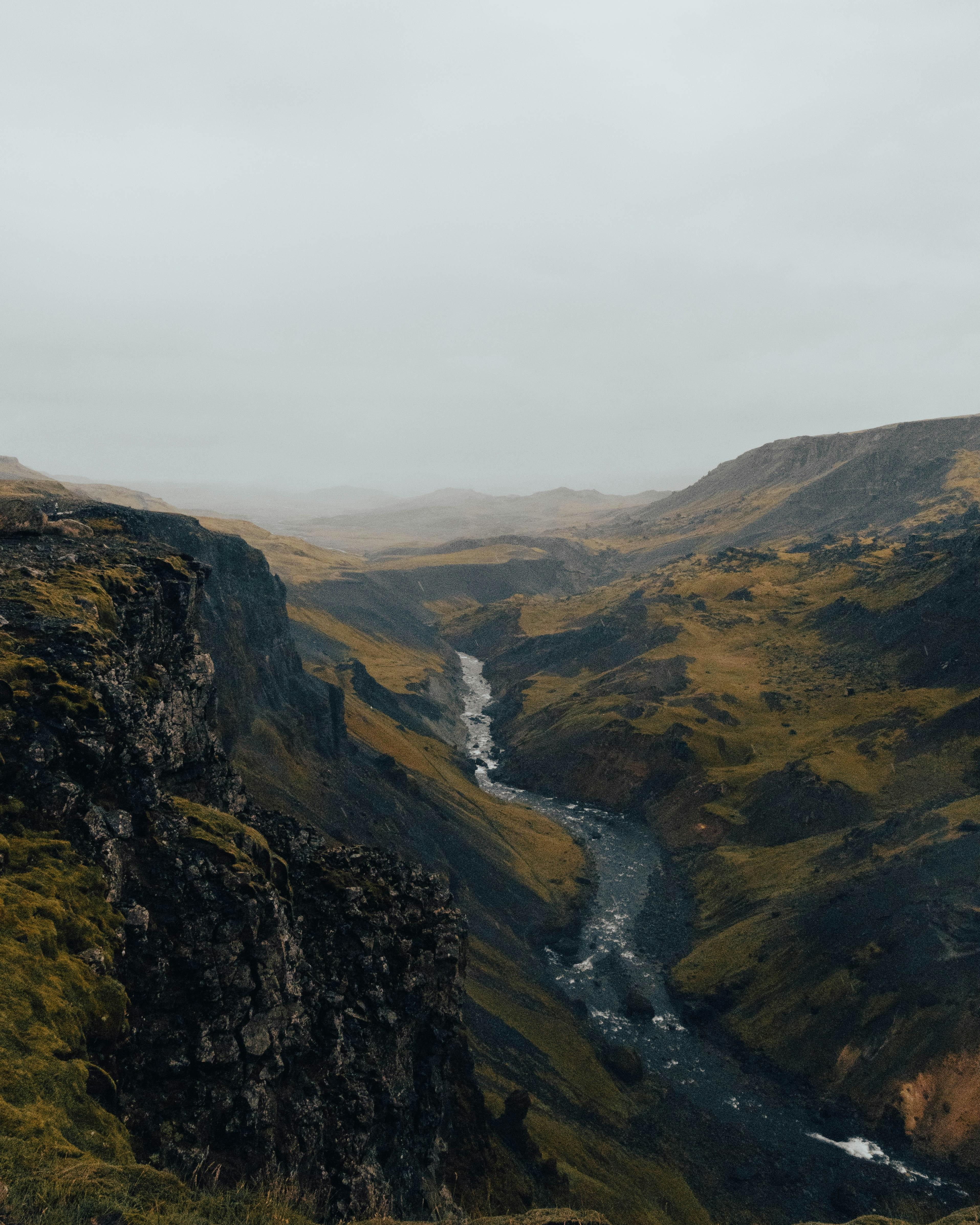 A breathtaking view of a moss-covered valley with a river flowing through it, showcasing the dramatic landscapes of Iceland's South Coast.