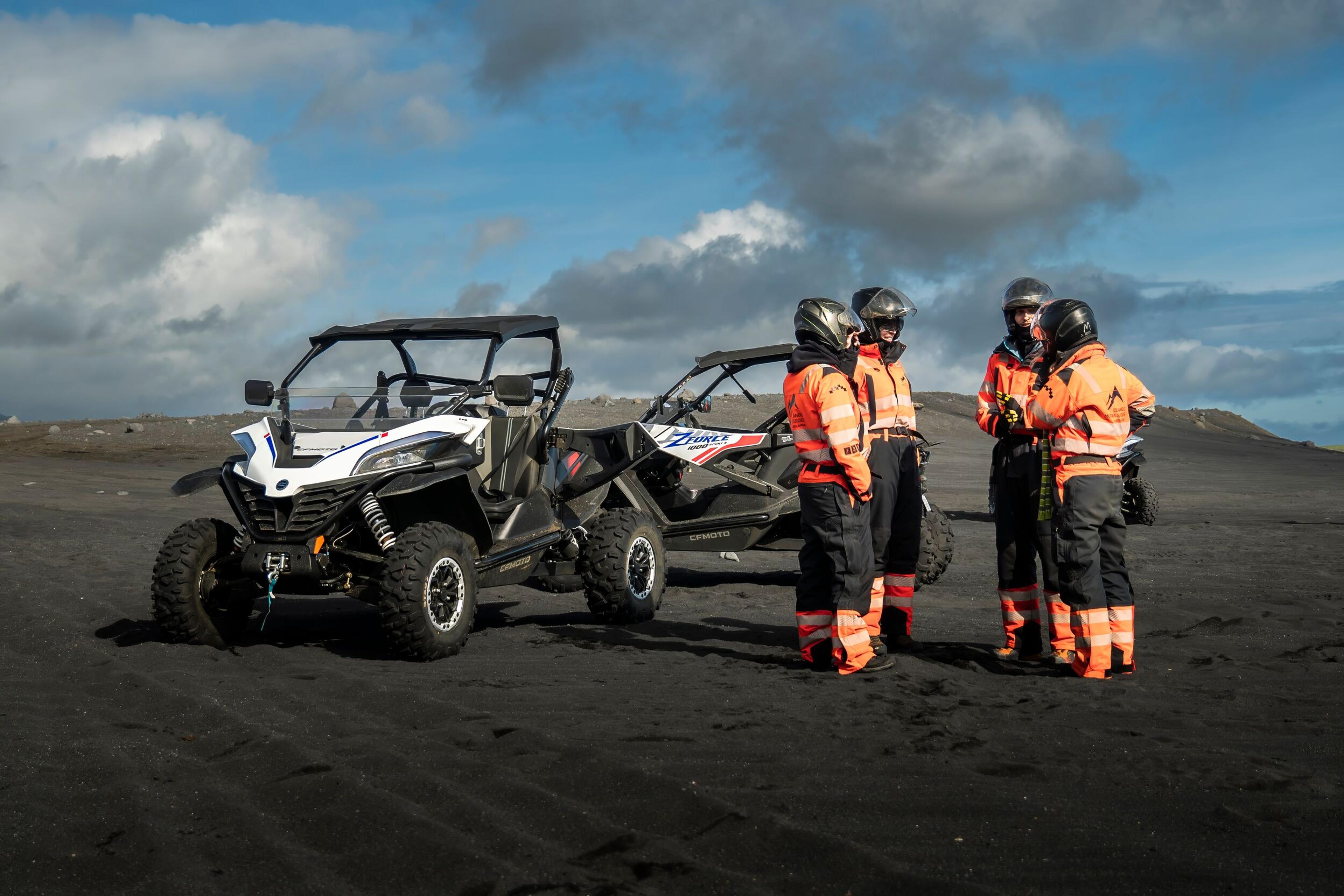 a group of people are standing next to two atvs on a dirt road .