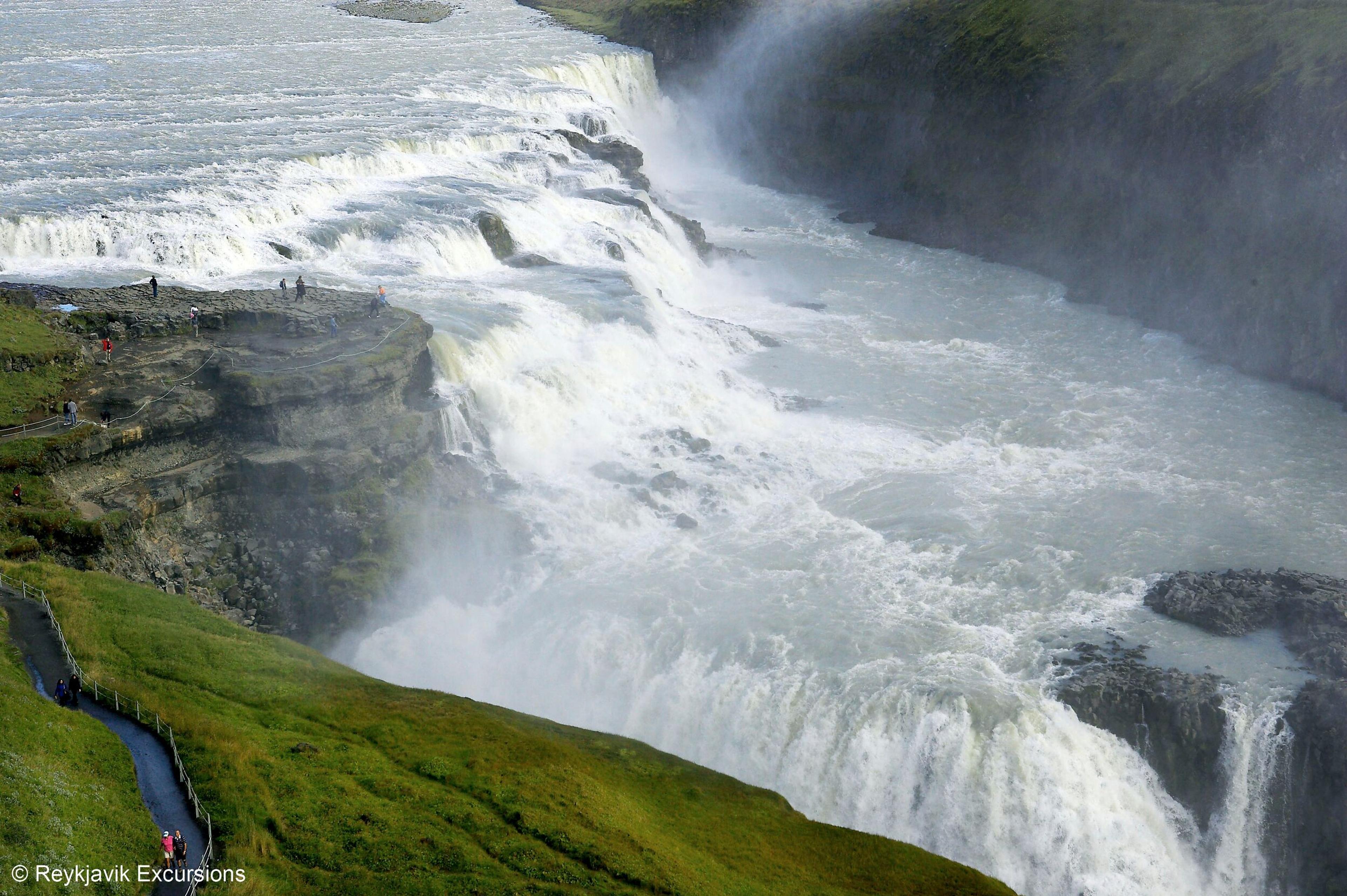 Closeóup image of Gullfoss waterfall with spectators standing in the viewing platform by the cascade