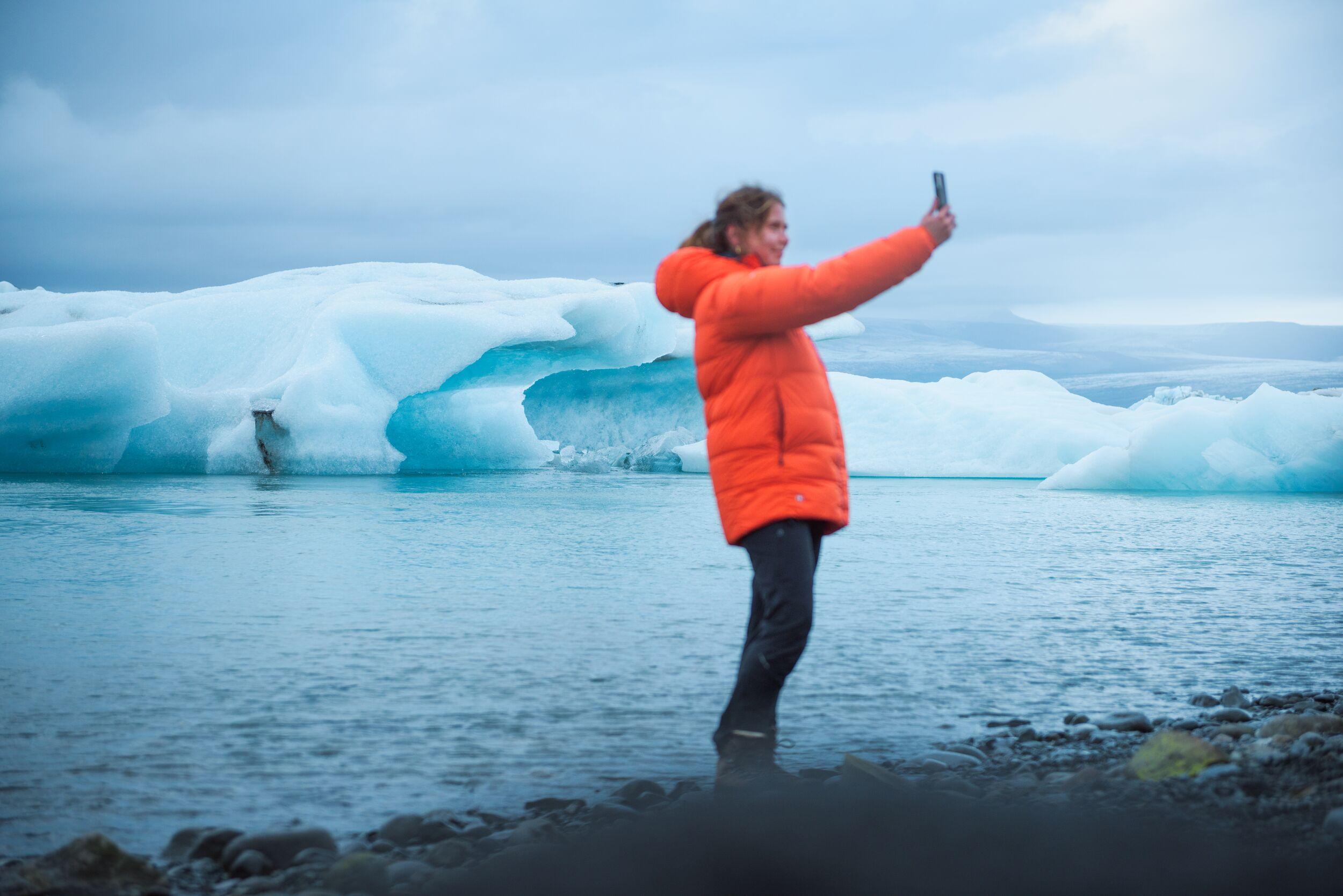 A woman looking at the calm icebergs floating on the glacial lagoon
