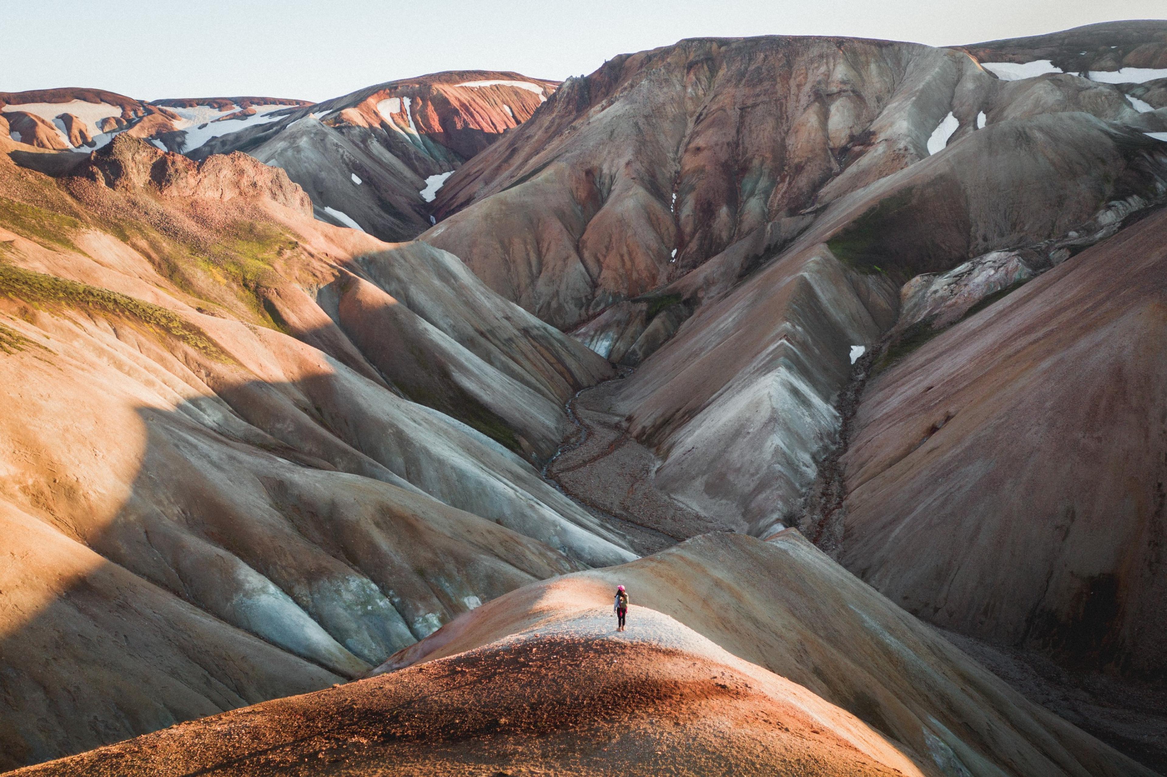 A person standing alone among the brown hills of Landmannalaugar