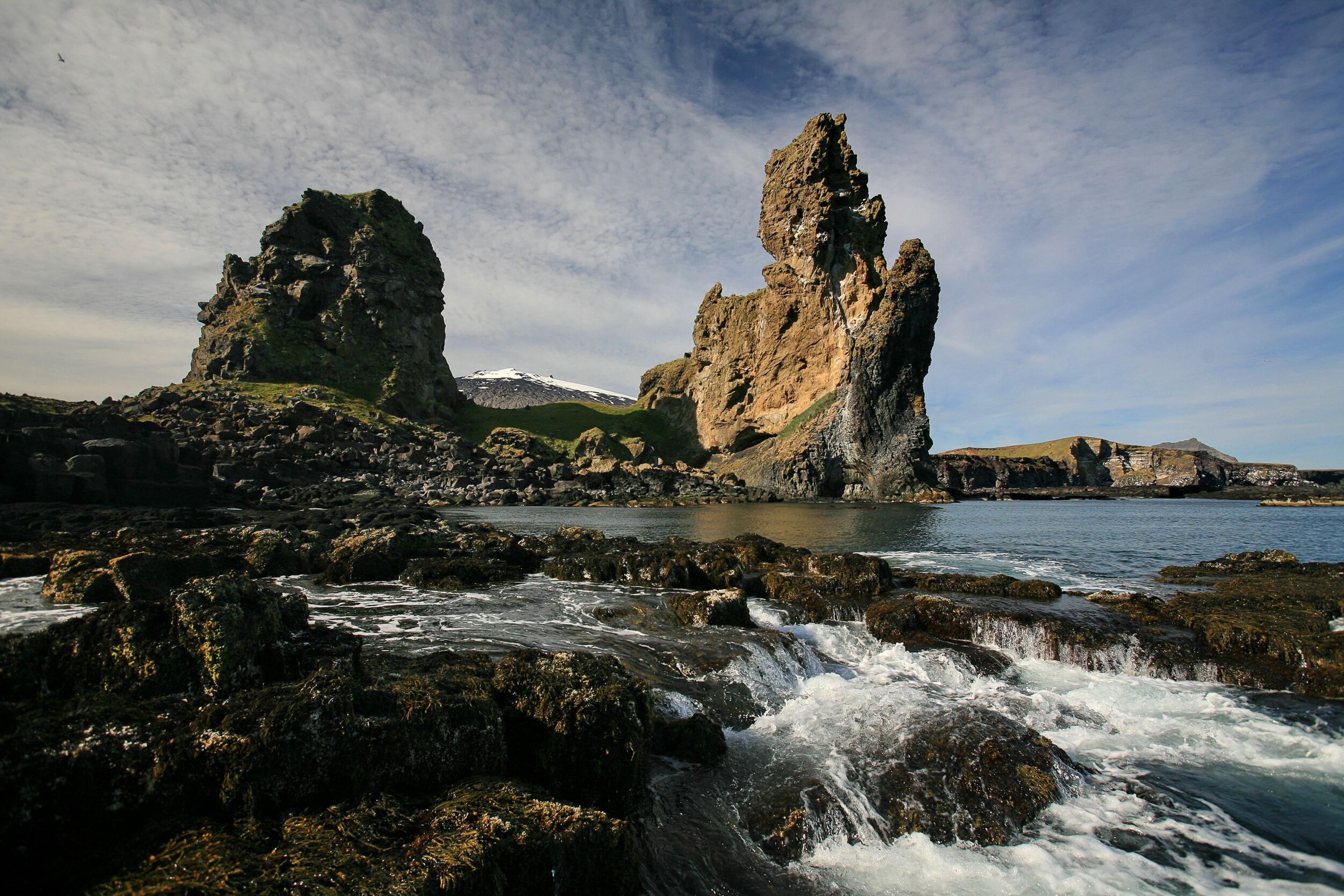 The rugged Longrangar sea cliffs in Iceland stretch along the coastline, with dramatic rock formations jutting into the ocean.