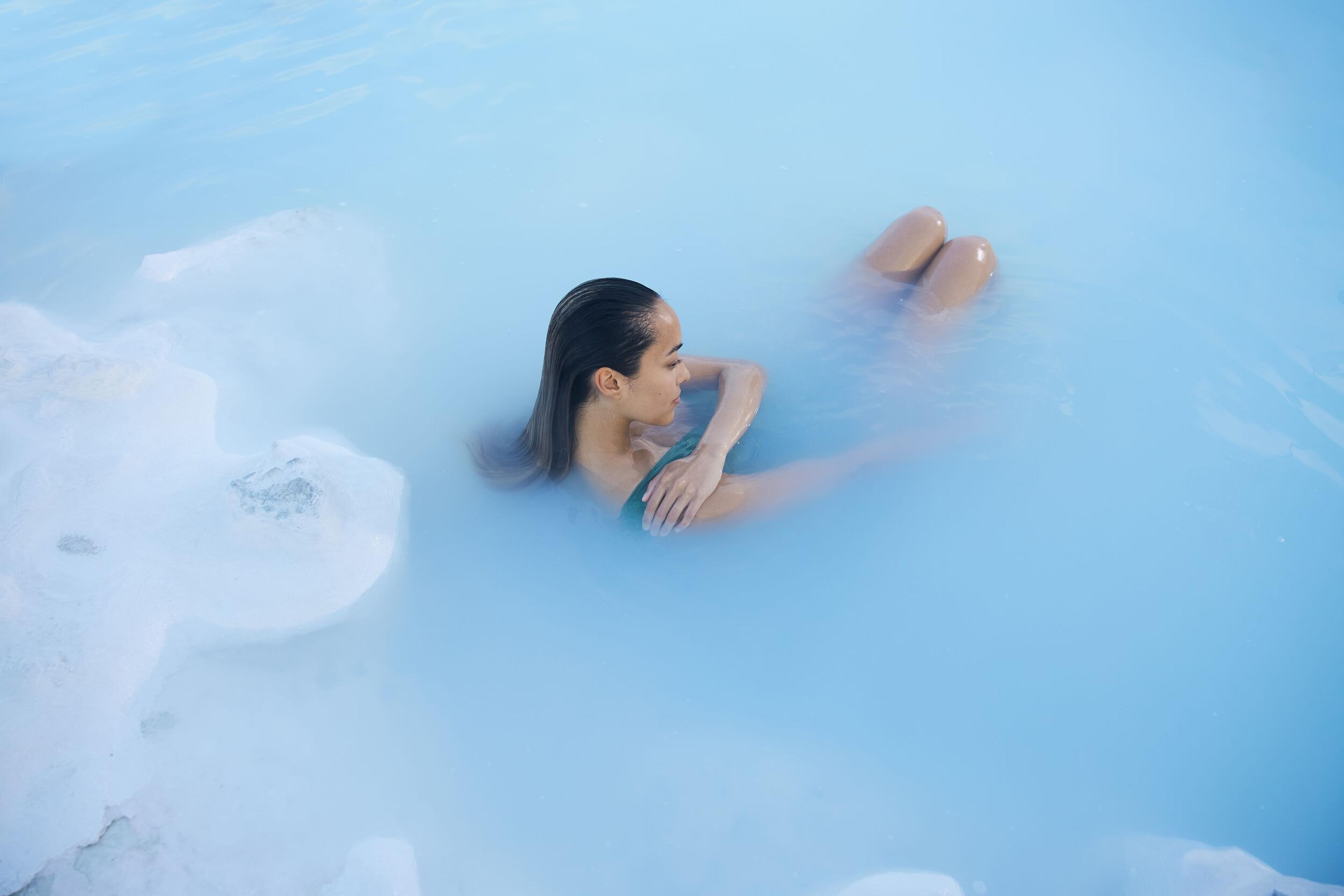 a woman soaking in the warma silica water of Blue Lagoon in Iceland.