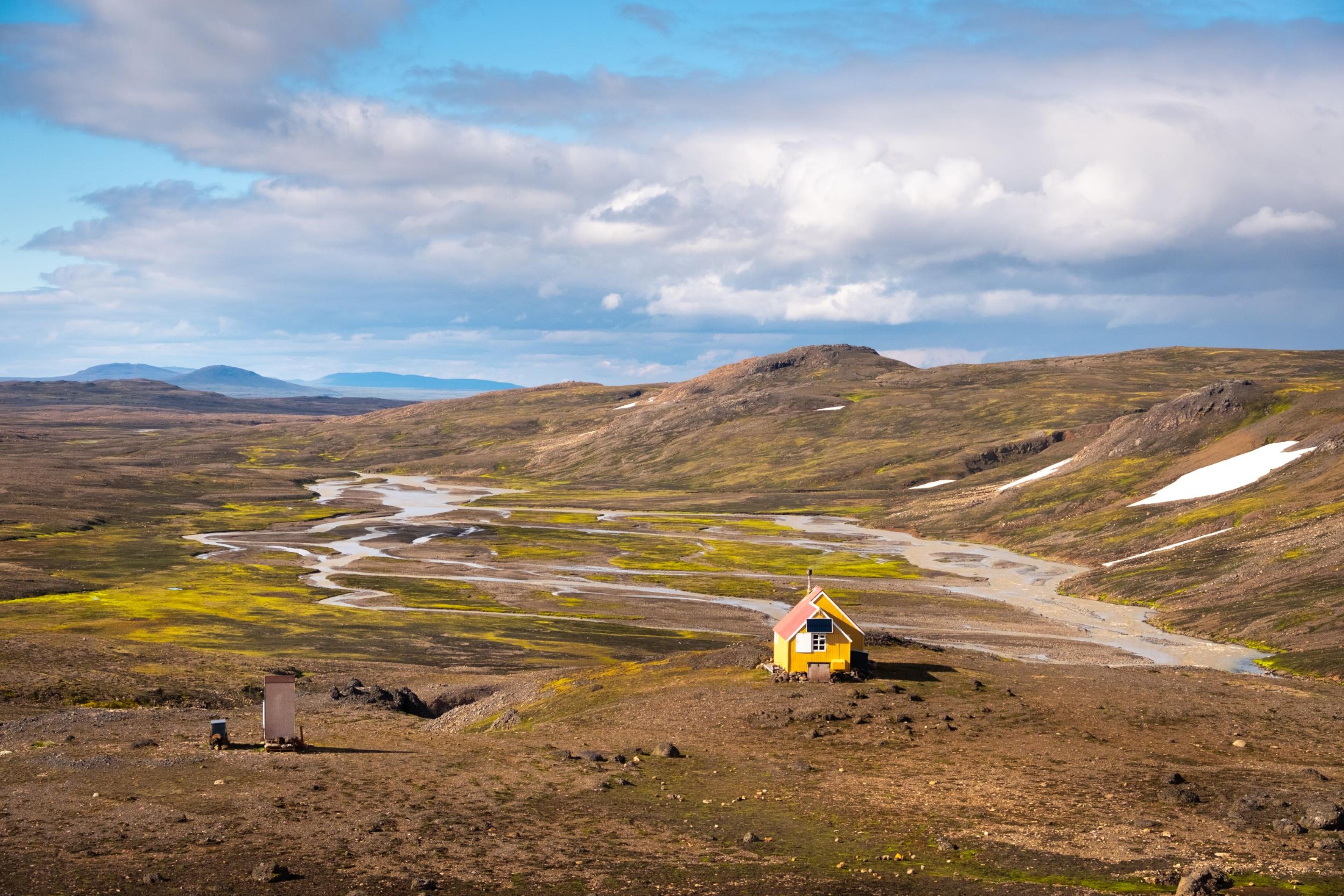 Small yellow hut nestled in a pristine and remote natural wilderness setting.