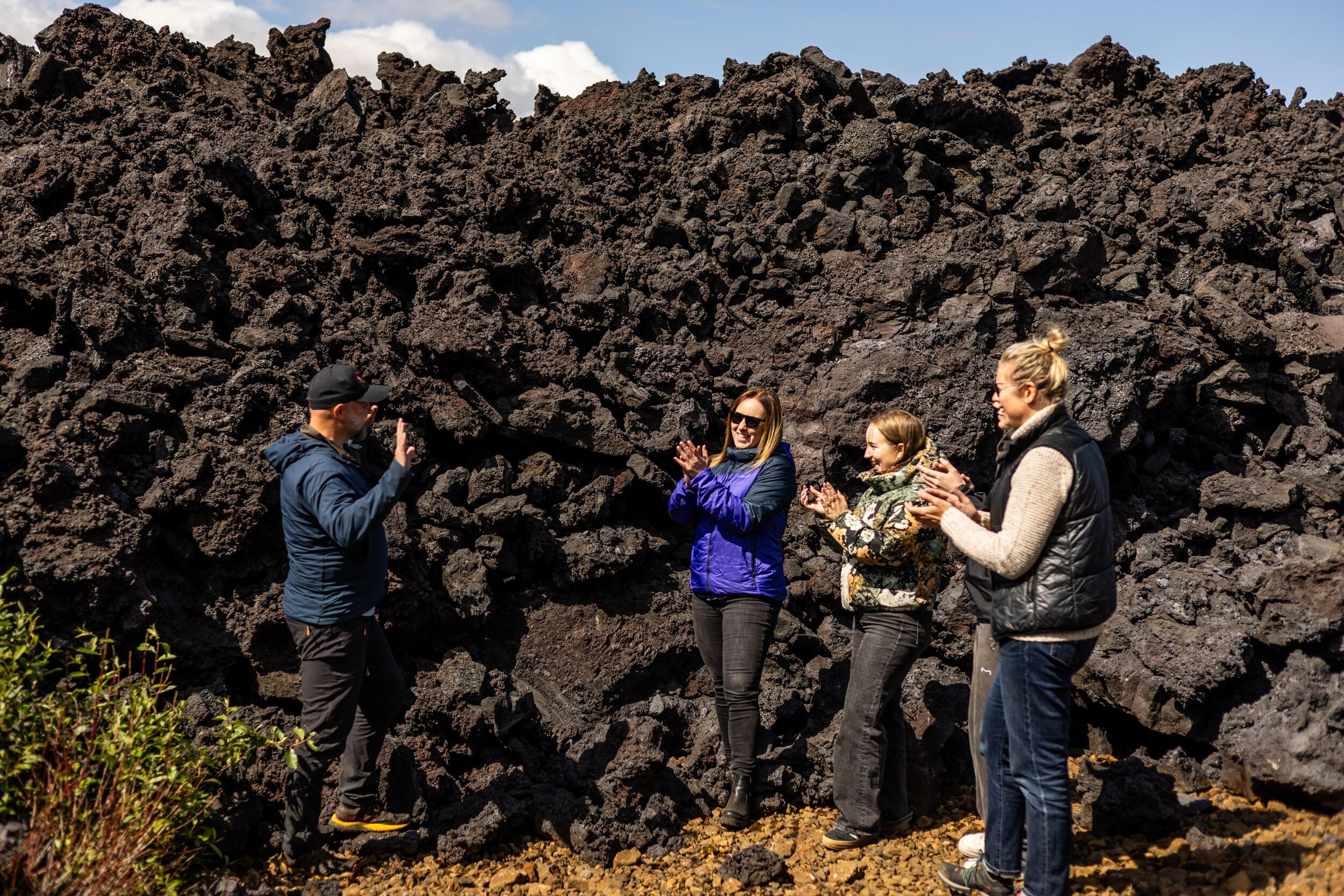 a group of people are standing in front of a large pile of rocks .