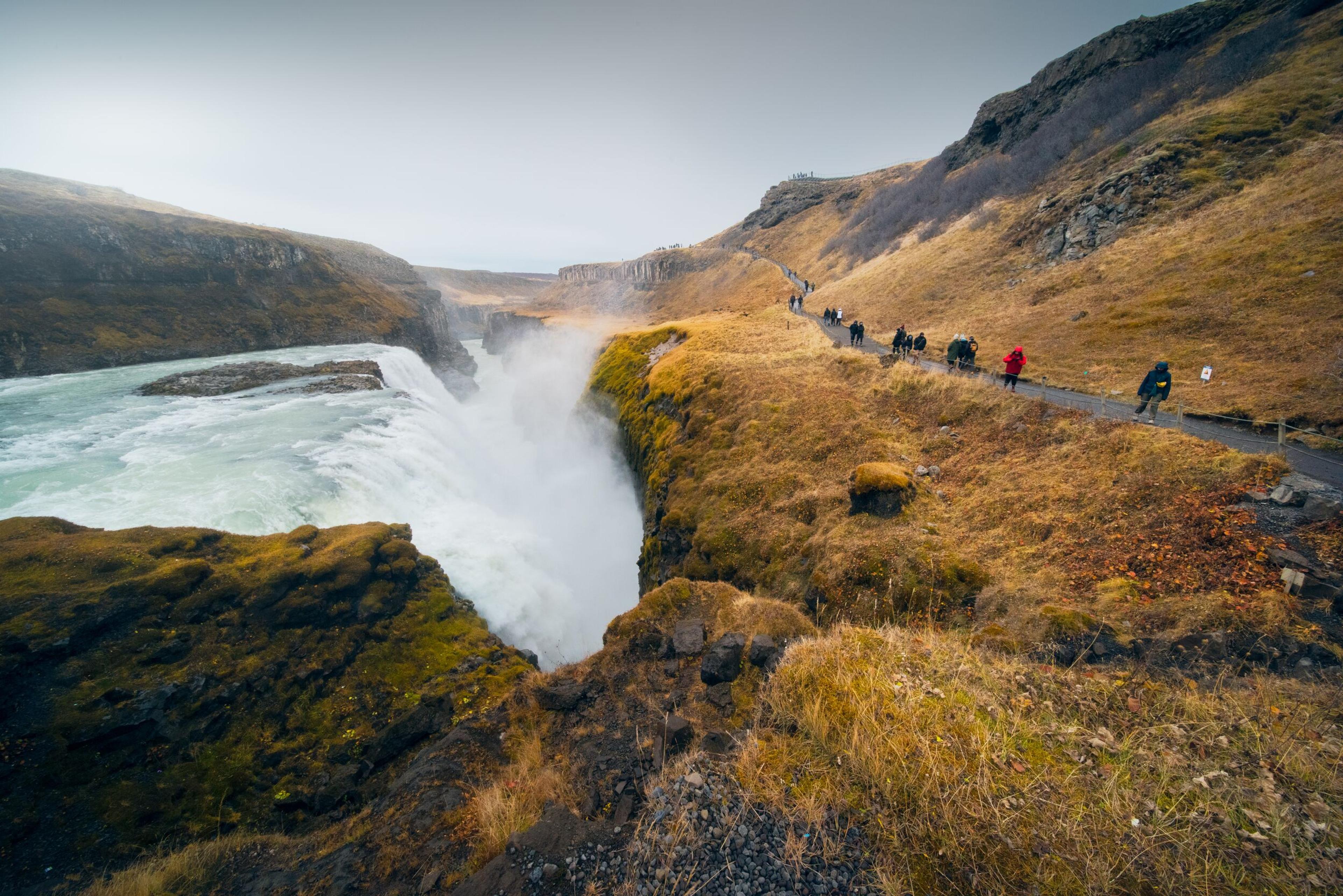  Gullfoss Waterfall in Iceland with cascading waters, surrounded by autumn foliage and rugged cliffs in the Golden Circle region.