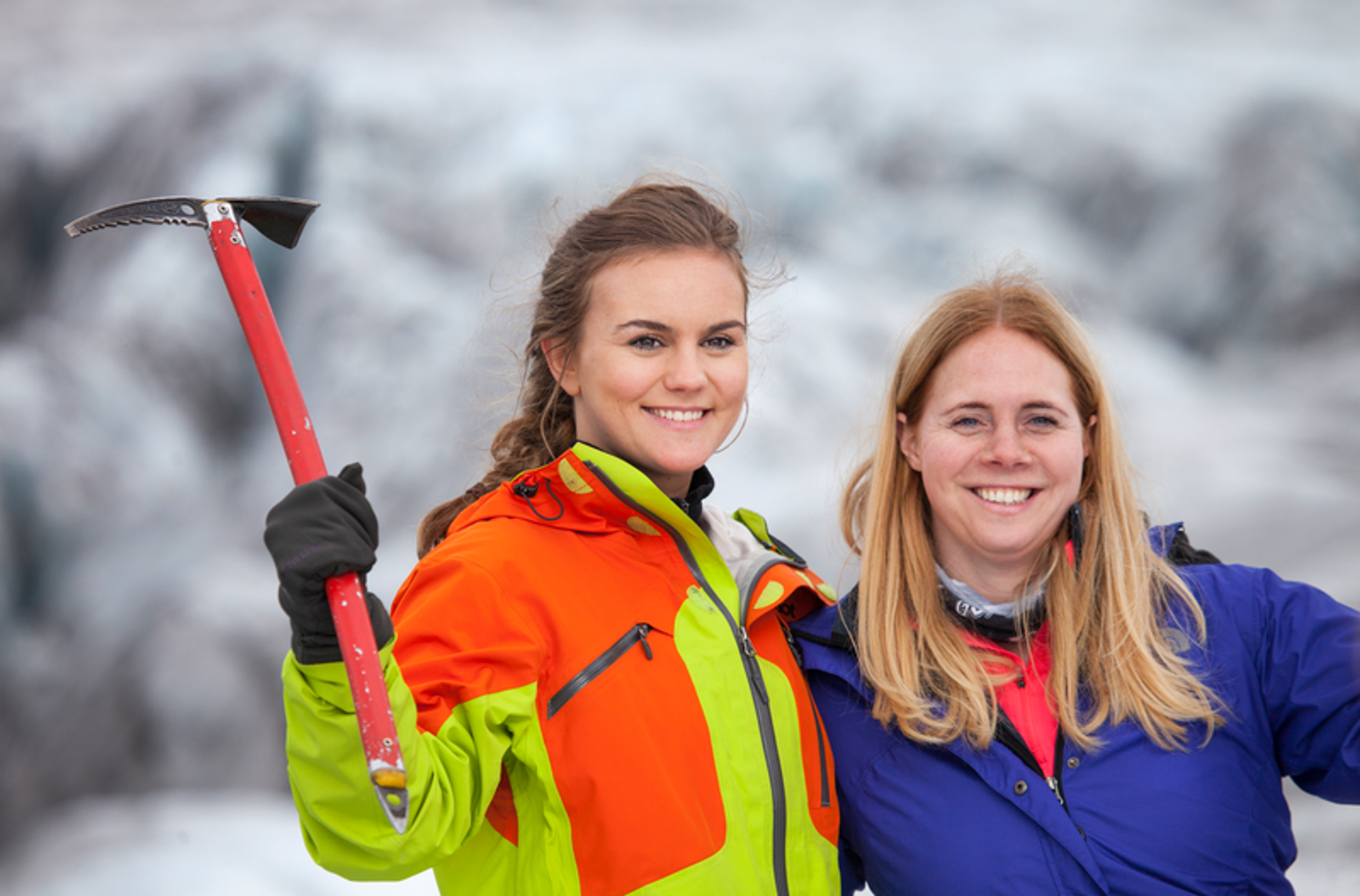 Two women smiling at a camera on top of a glacier in iceland.