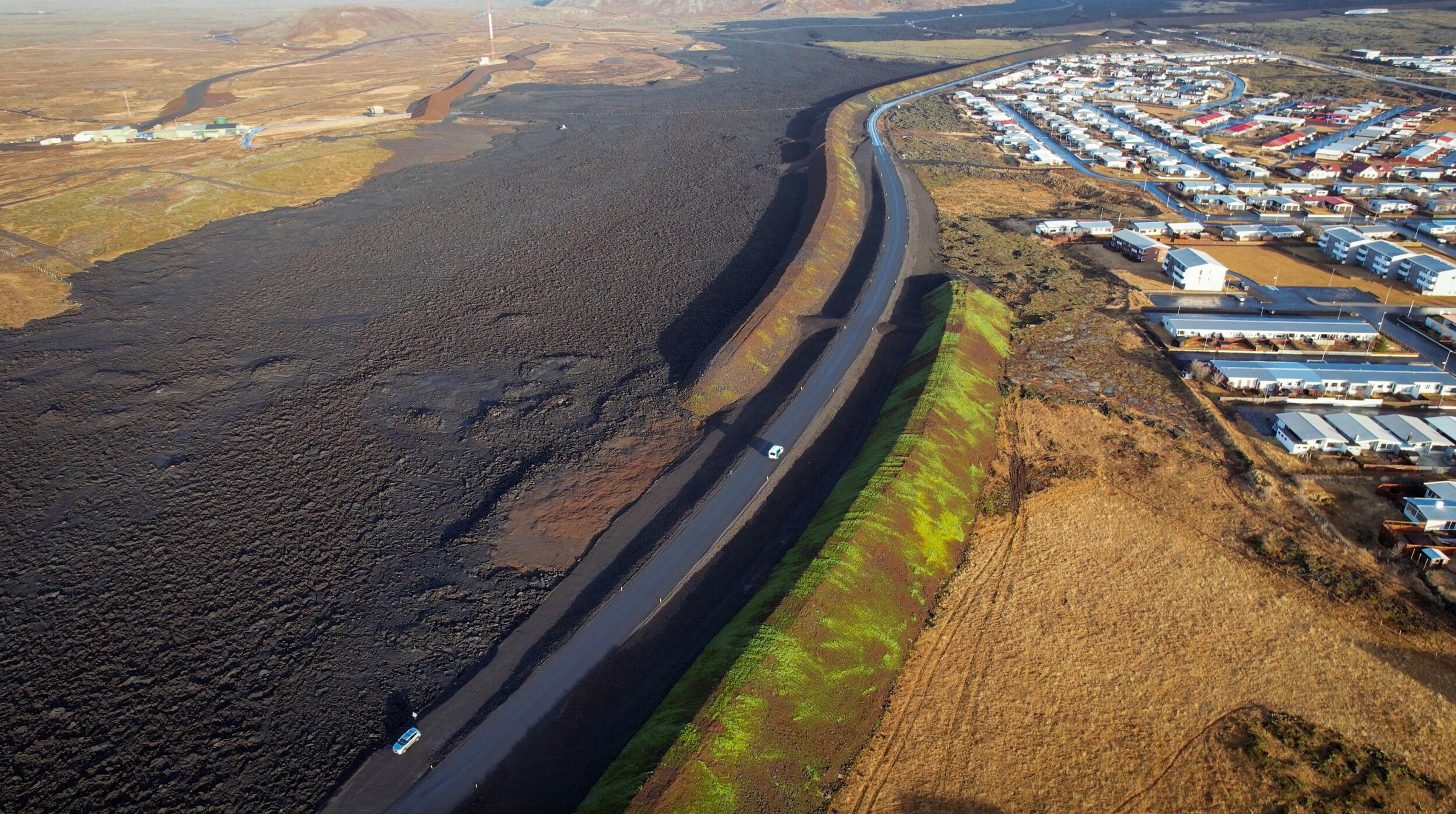 an aerial view of a car driving down a road next to a river .
