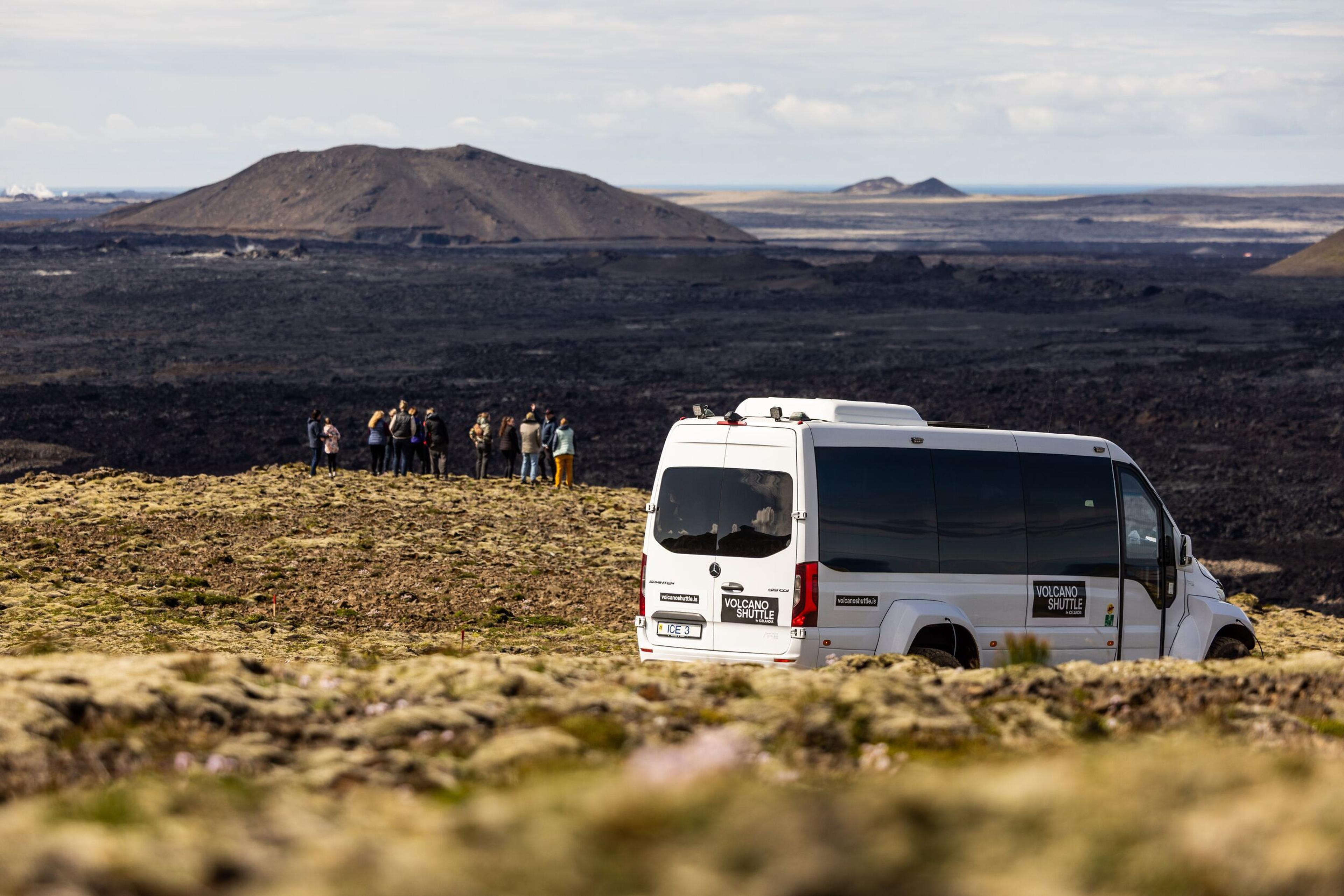 a group of people are standing on top of a hill next to a van .