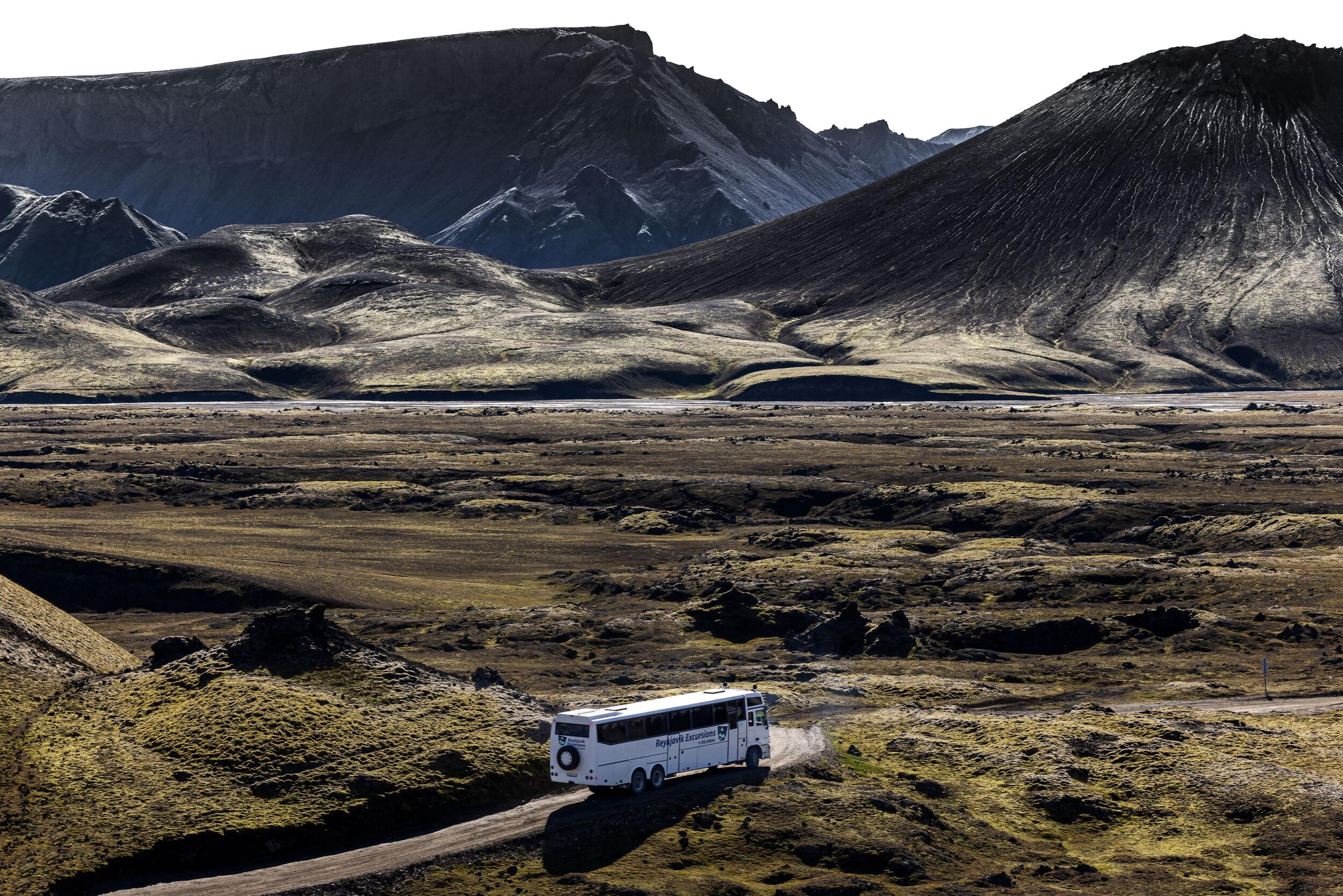 A white bus with modified large wheels crossing the Icelandic Highlands