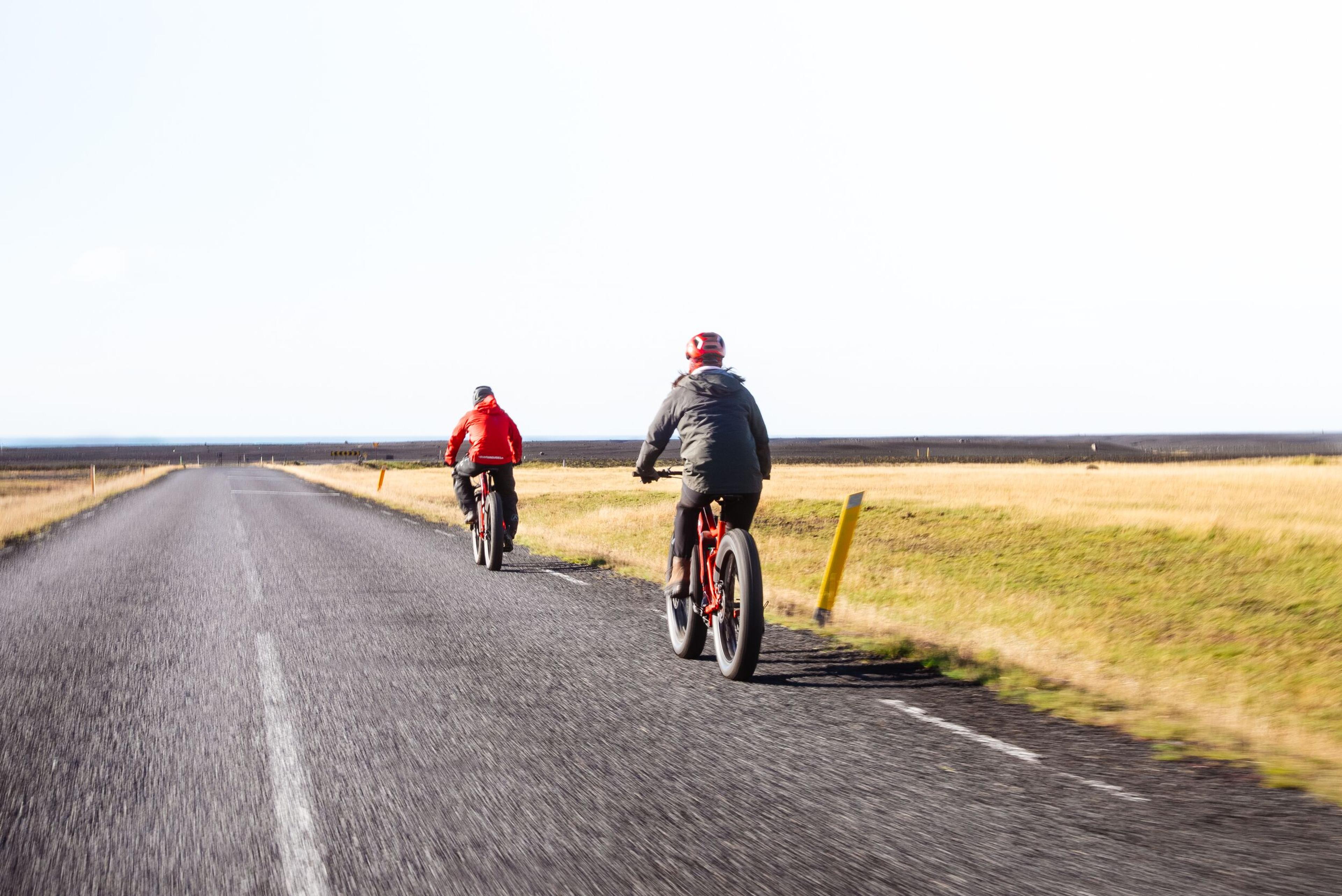 two people are riding bicycles down a road .