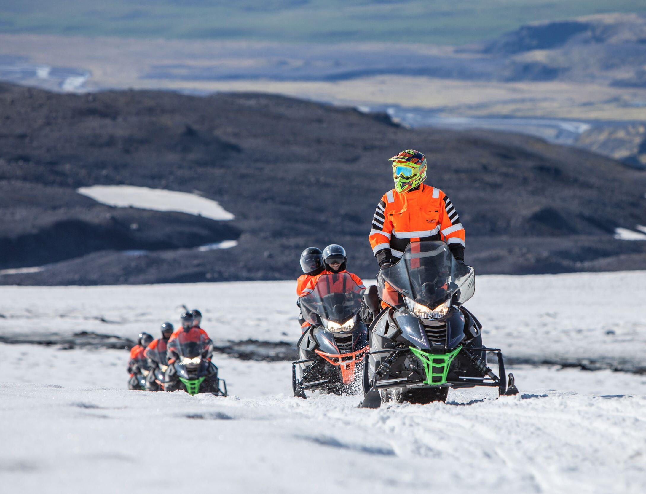 A group of explorers on snowmobile riding through the Mýrdalsjökull Glacier.