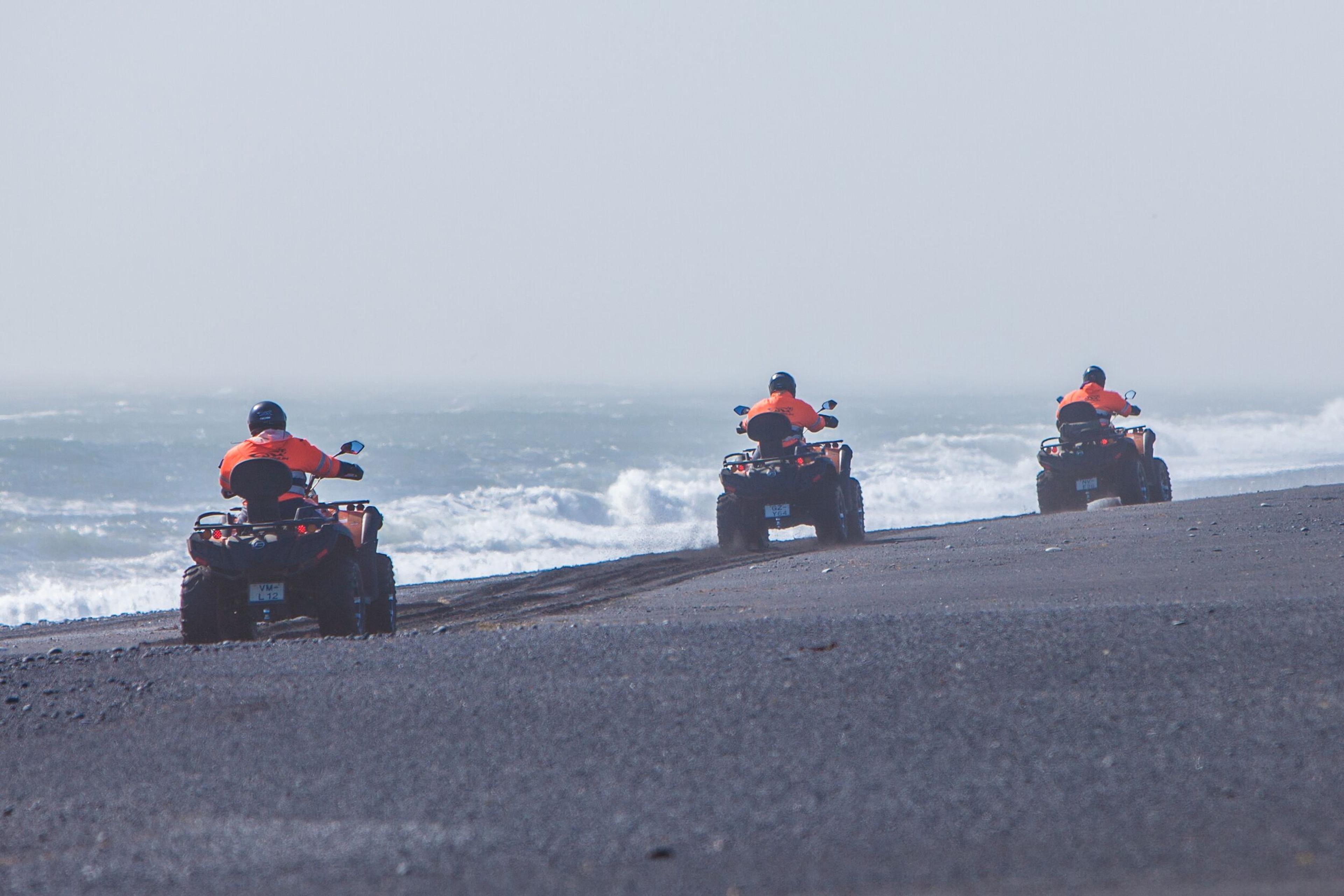 atv bikes traveling through a black sand beach in Iceland.