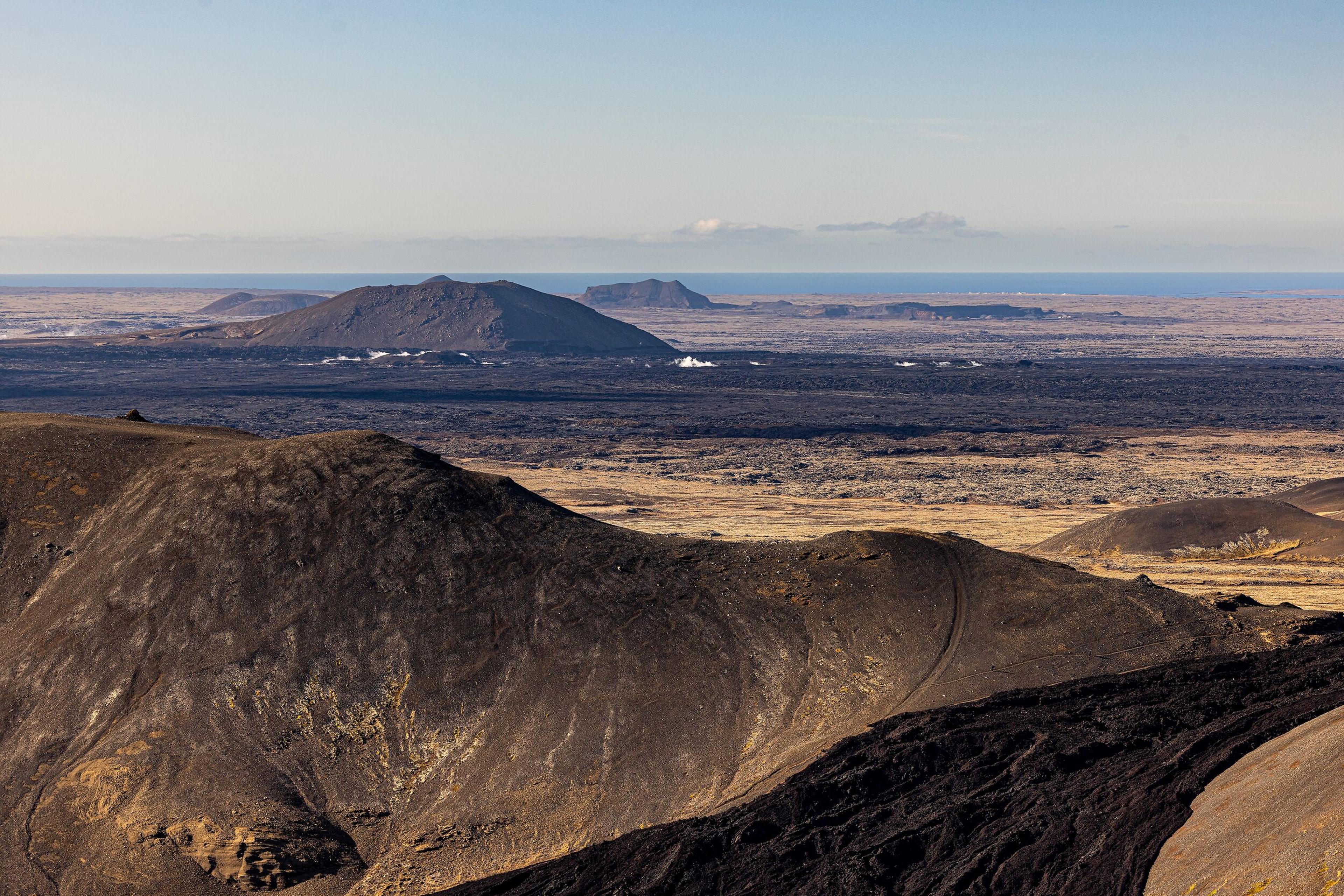  Panoramic image of Reykjanes Peninsula, showcasing rugged volcanic hills and the expansive landscape extending towards the distant ocean.