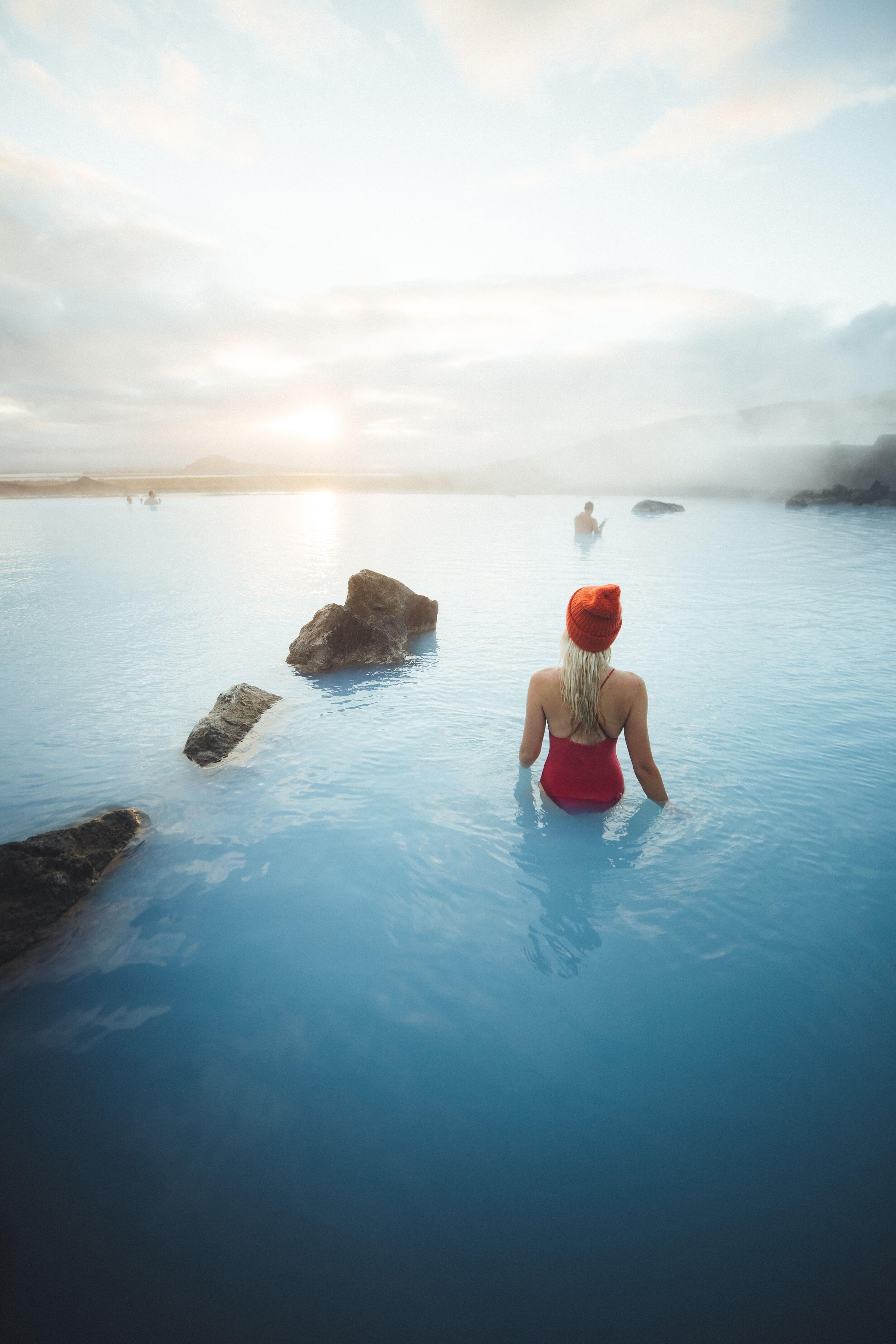 a woman in a red bathing suit is sitting in a pool of blue water .