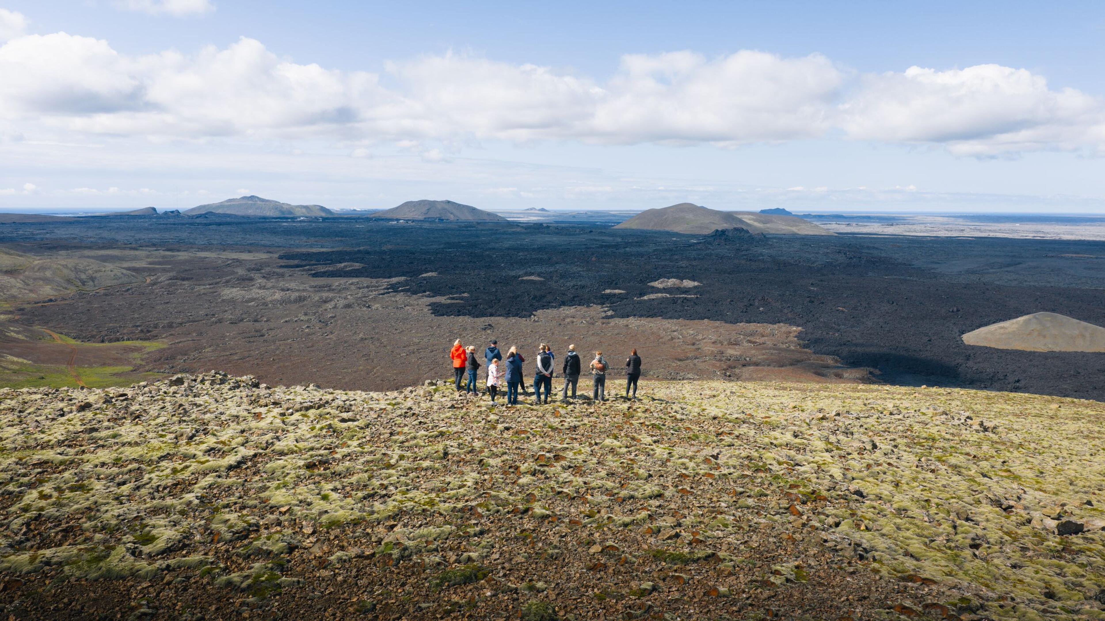 a group of people are standing on top of a mountain in front of a new lava