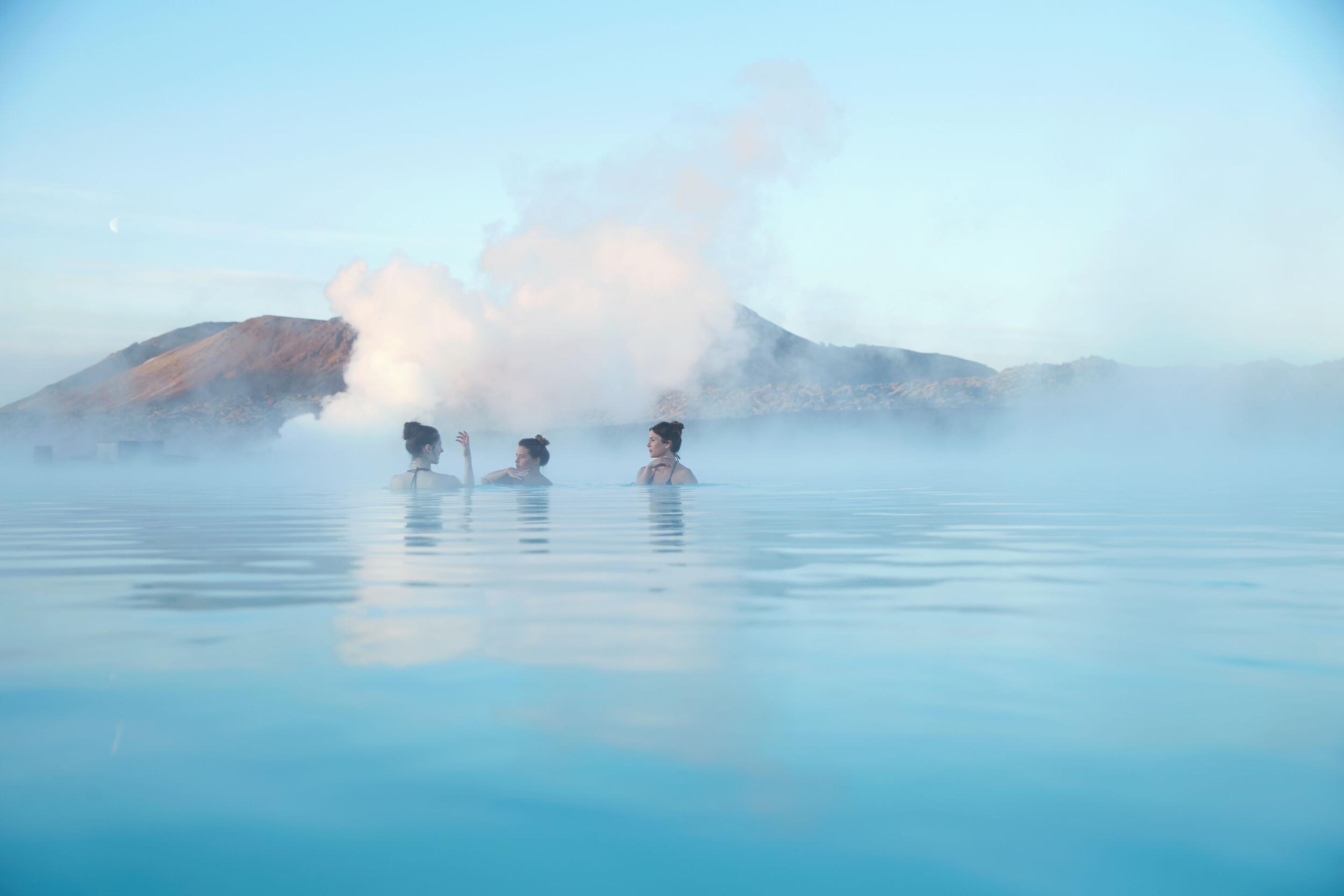 hree women in Blue Lagoon, steam rising in background