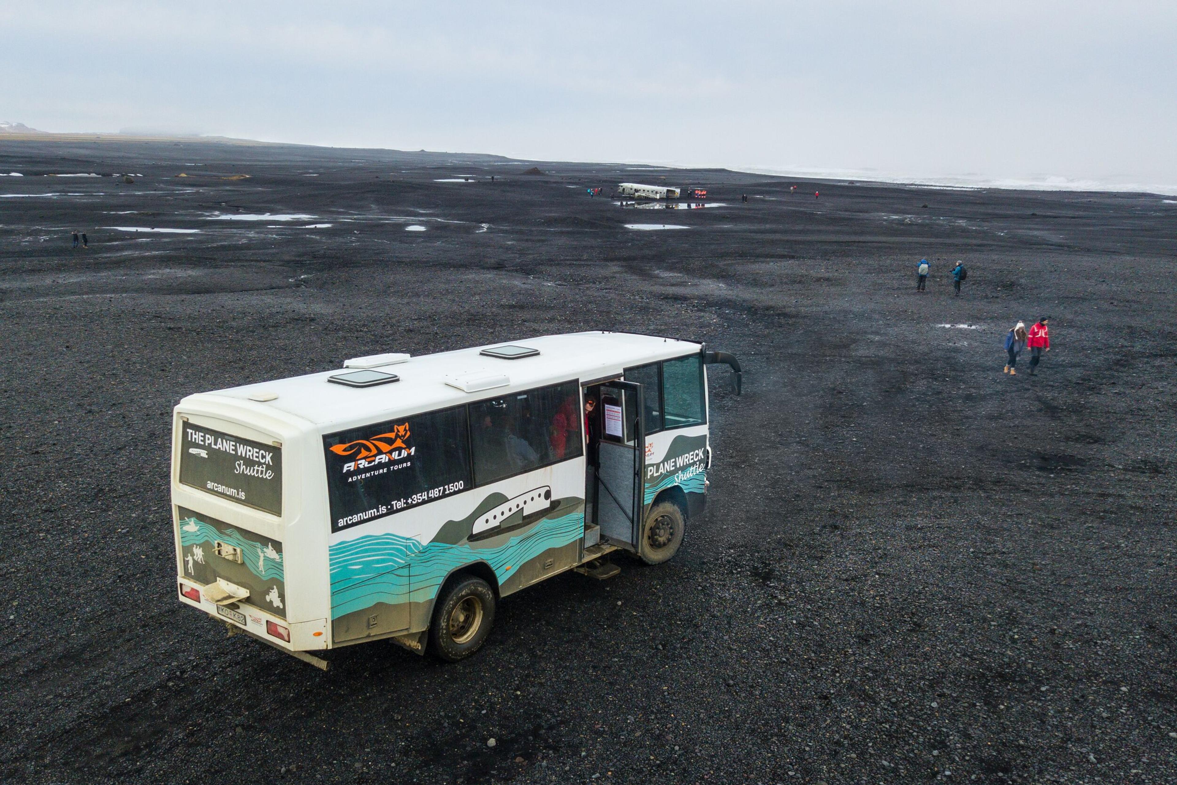 Plane wreck Shuttle driving through black sand beach in the south coast of Iceland.