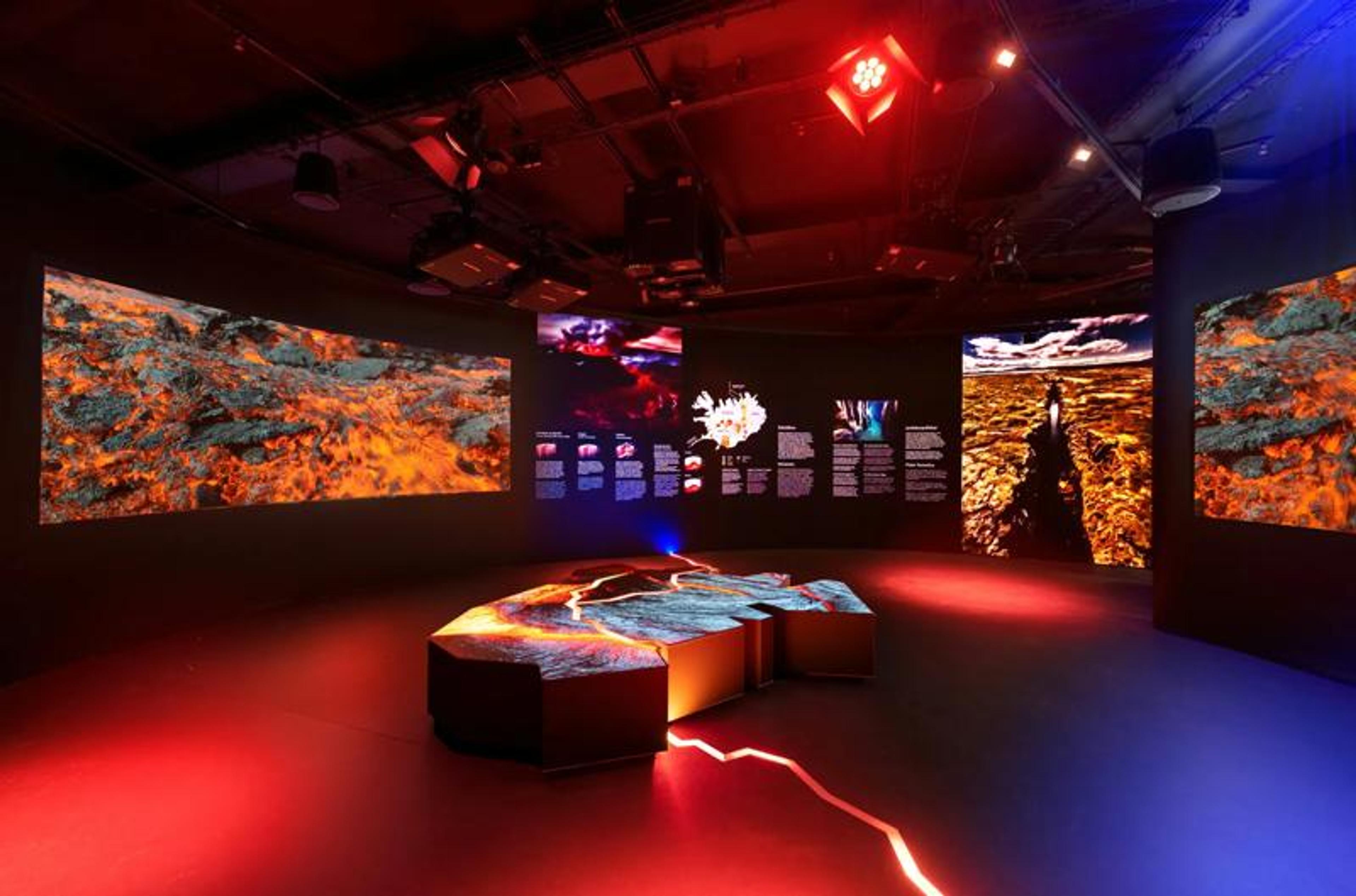 Volcanic-themed exhibition with lava displays on screens, a glowing central relief map, and dynamic red and blue lighting.