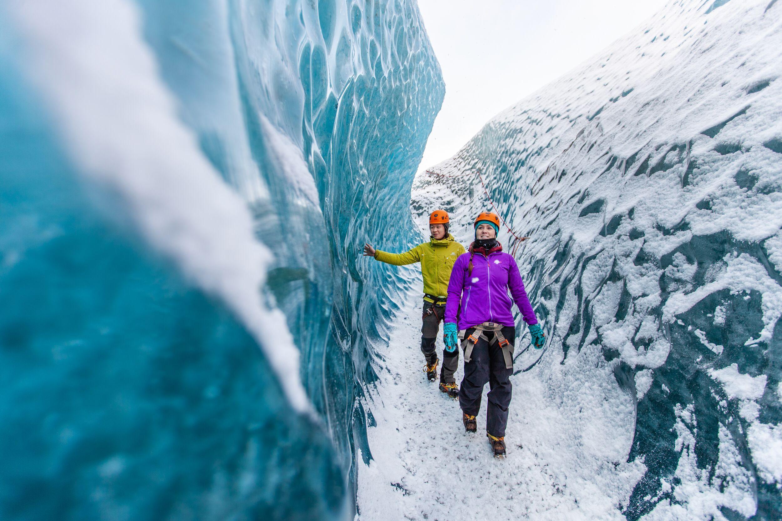 a man and a woman are walking through an ice cave .