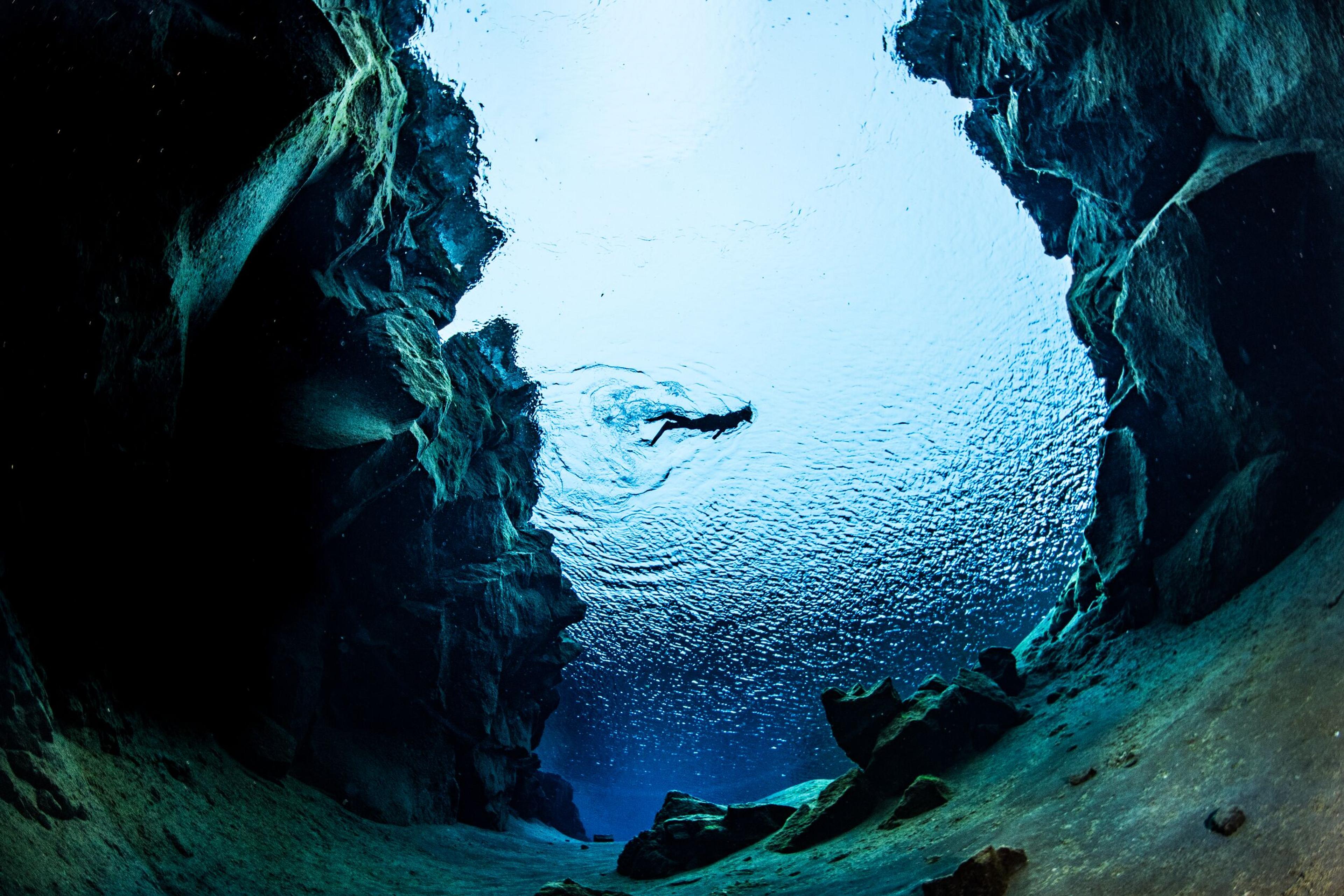Snorkeler floating on the surface, peering down into the chasm between tectonic plates.