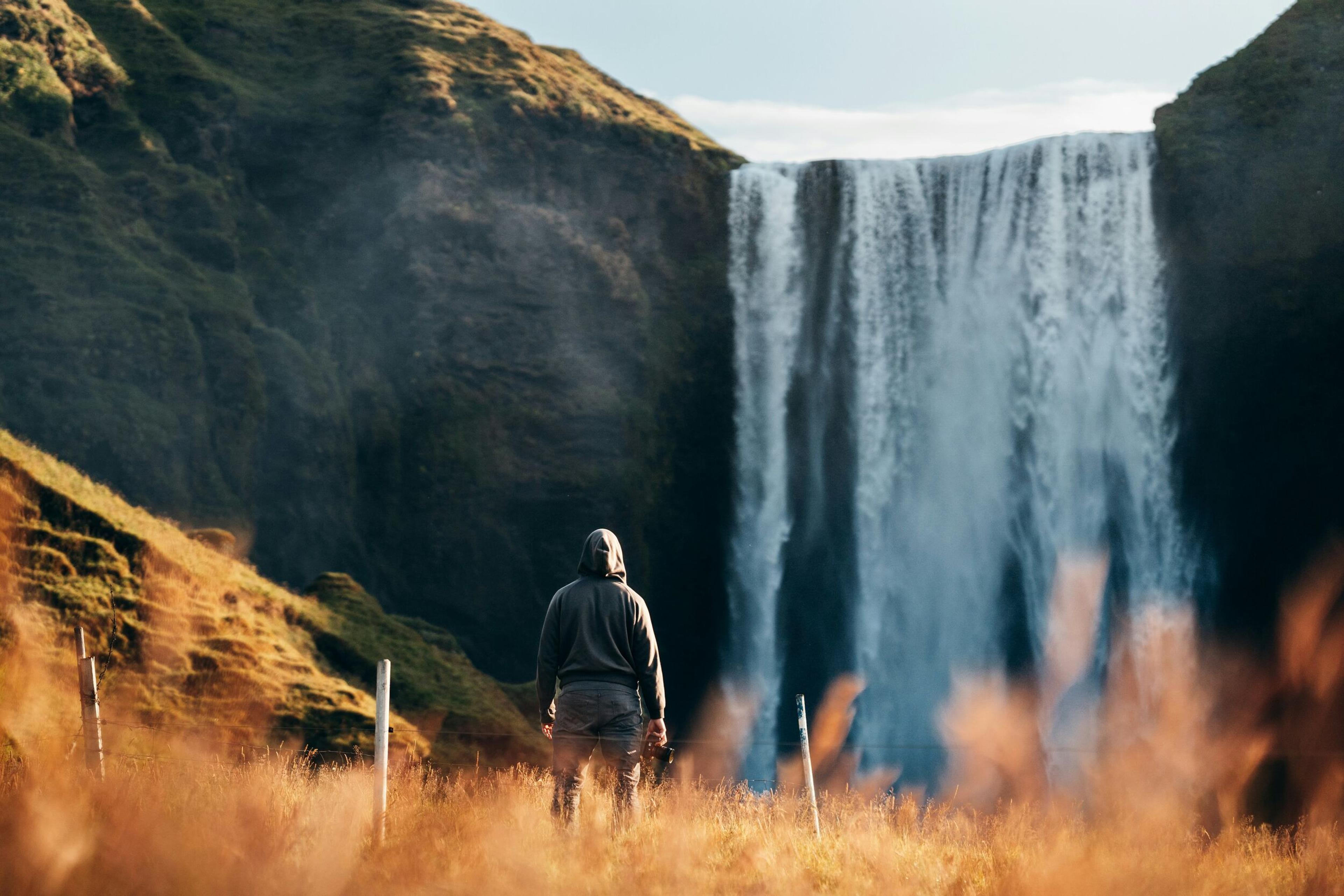  A man stands in front of Iceland's iconic Skógafoss waterfall, admiring its powerful flow on the South Coast.