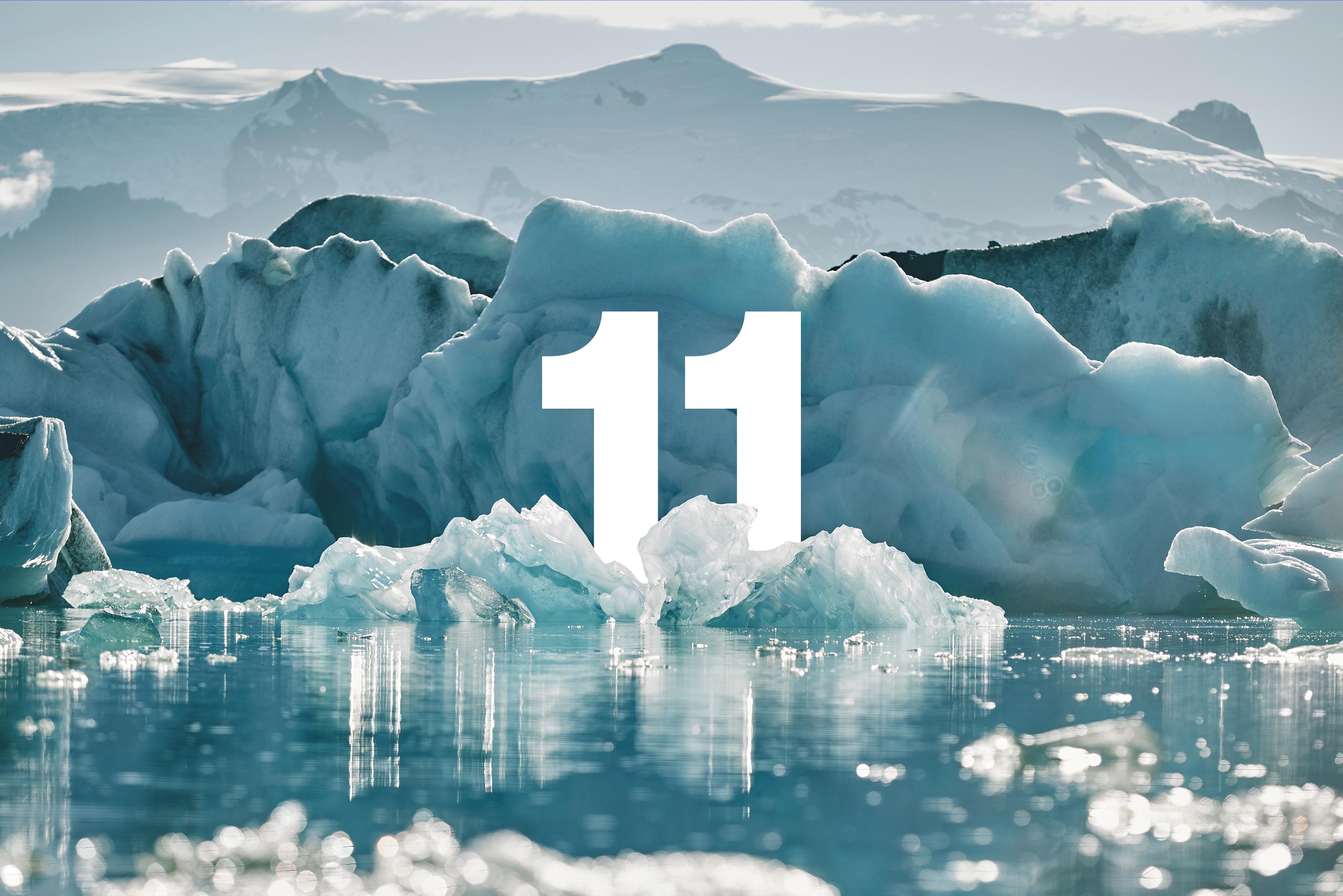 White number 11 on a glacial lake with icebergs and mountains.
