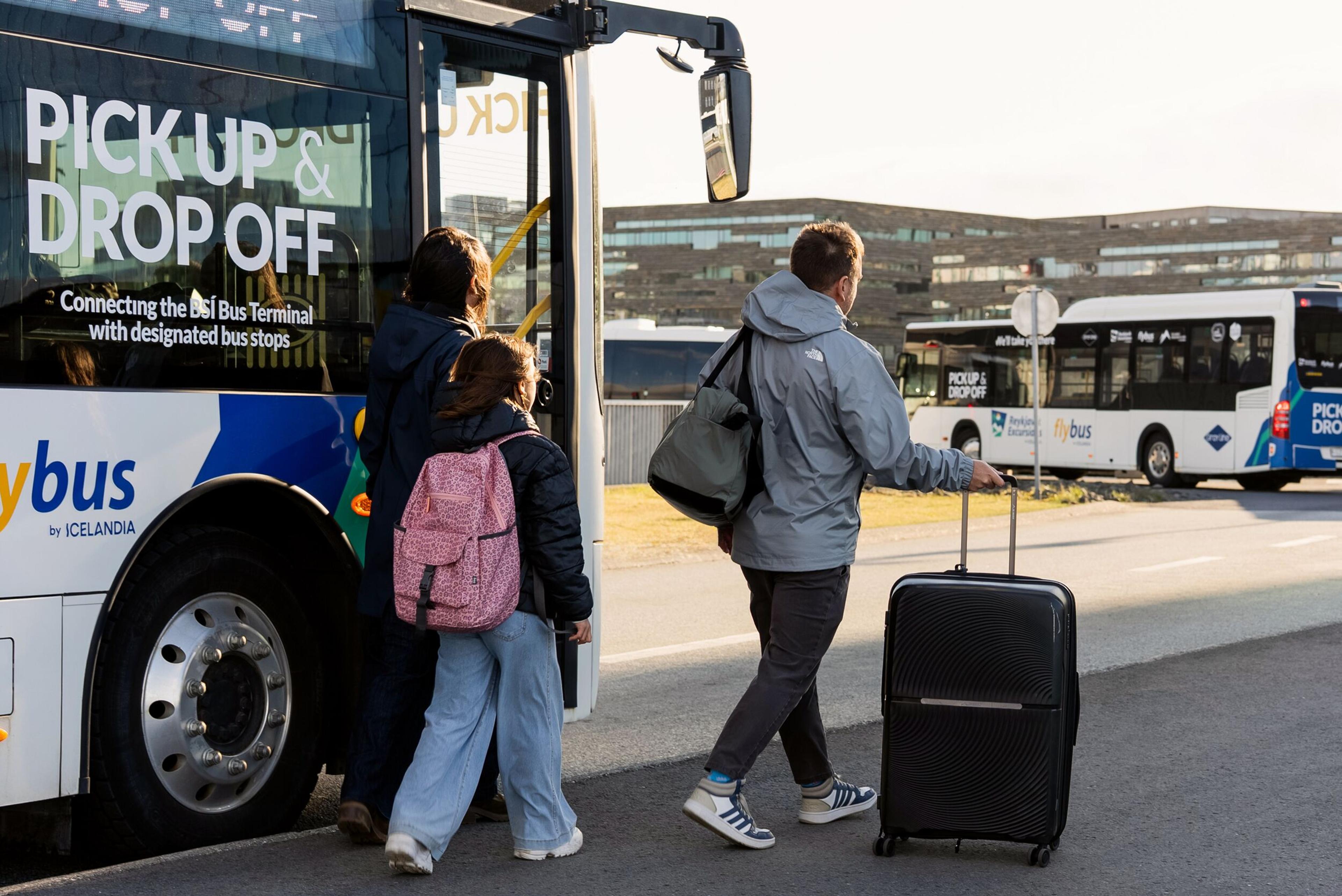 Passengers with luggage boarding a Flybus shuttle bus.