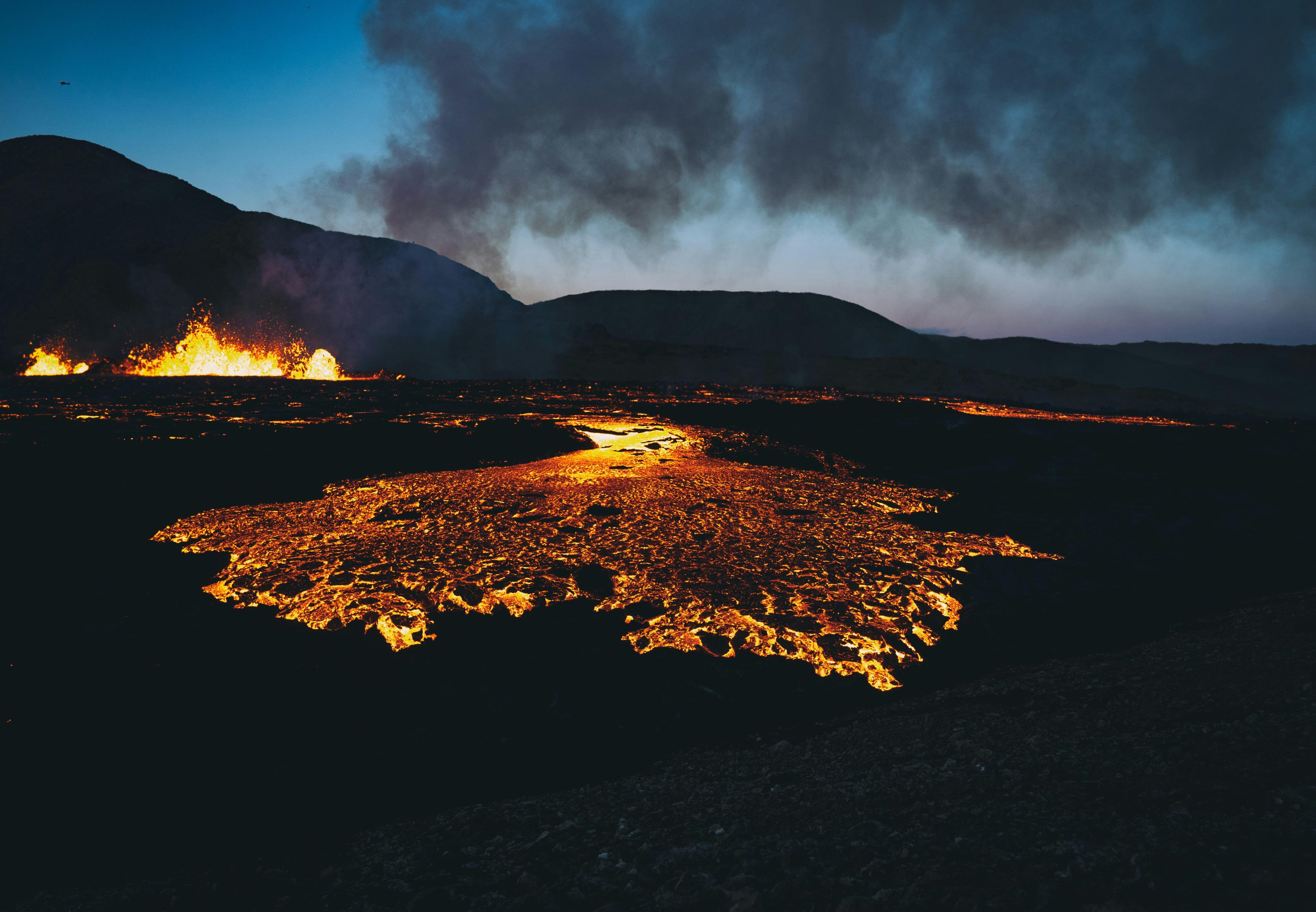 Icelandic volcano with orange lava erupting.