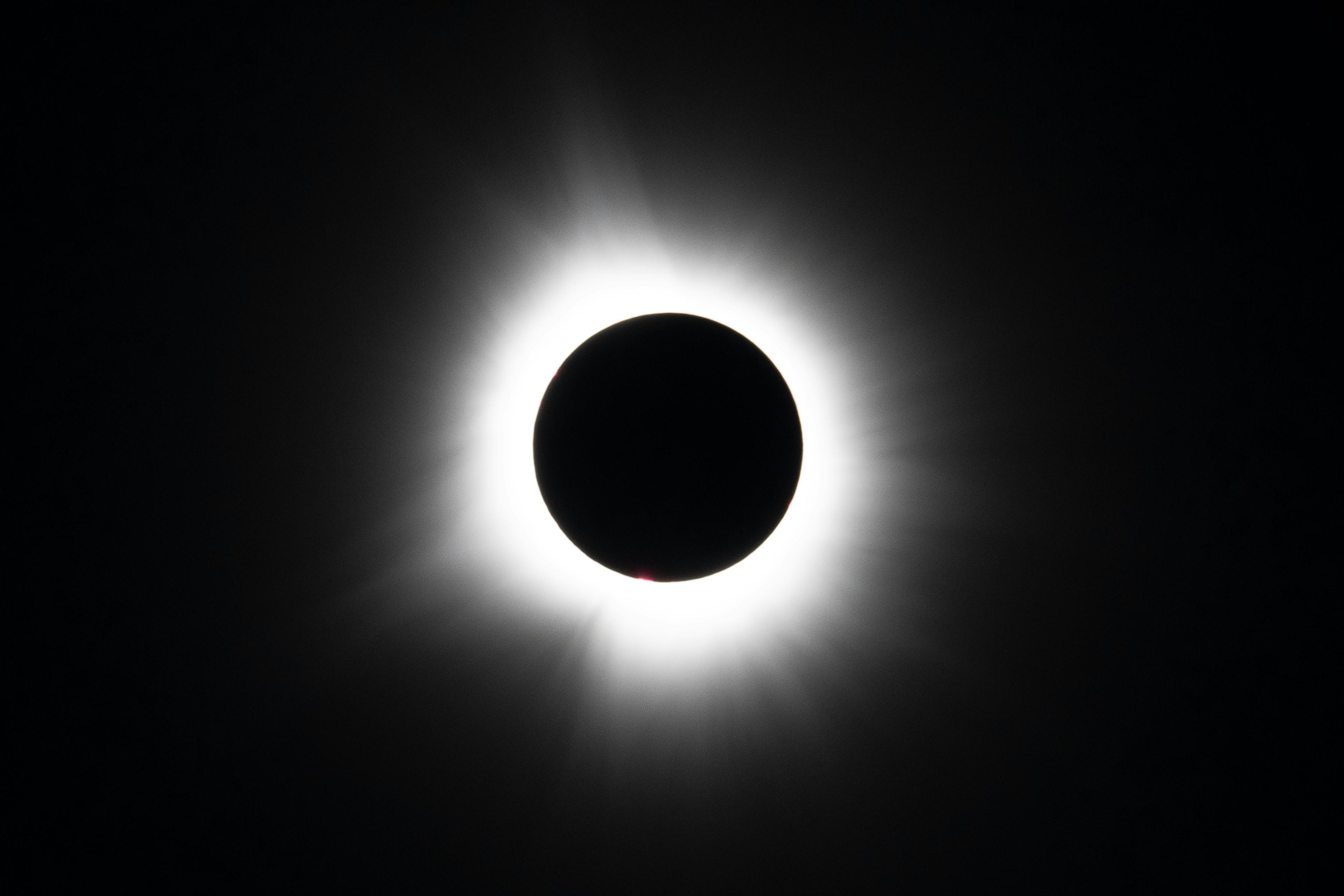 A total solar eclipse, with the sun's light peeking out from behind the moon, creating a bright flash against the dark sky.