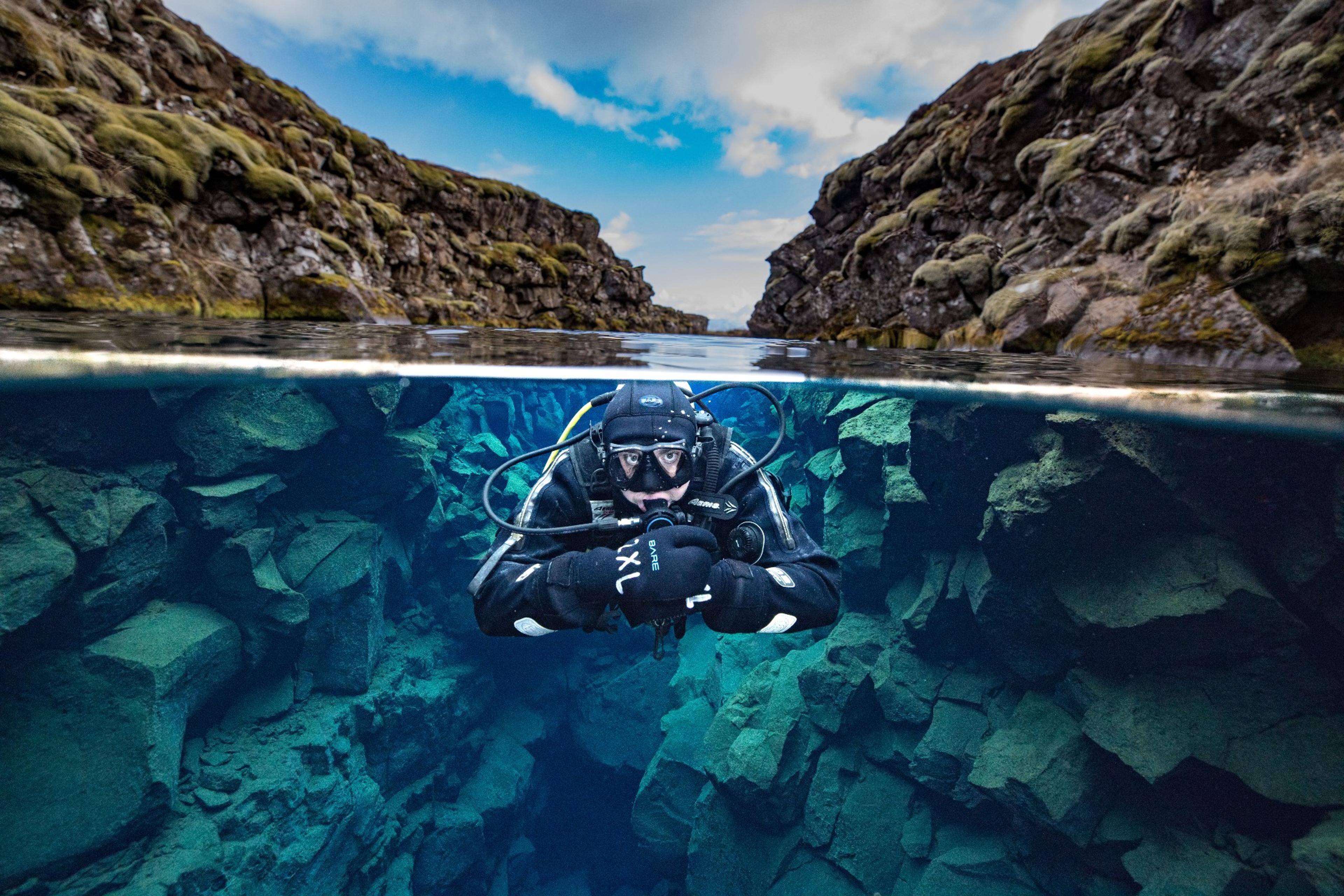 Person diving in Silfrá river in Þingvellir National Park, Iceland.