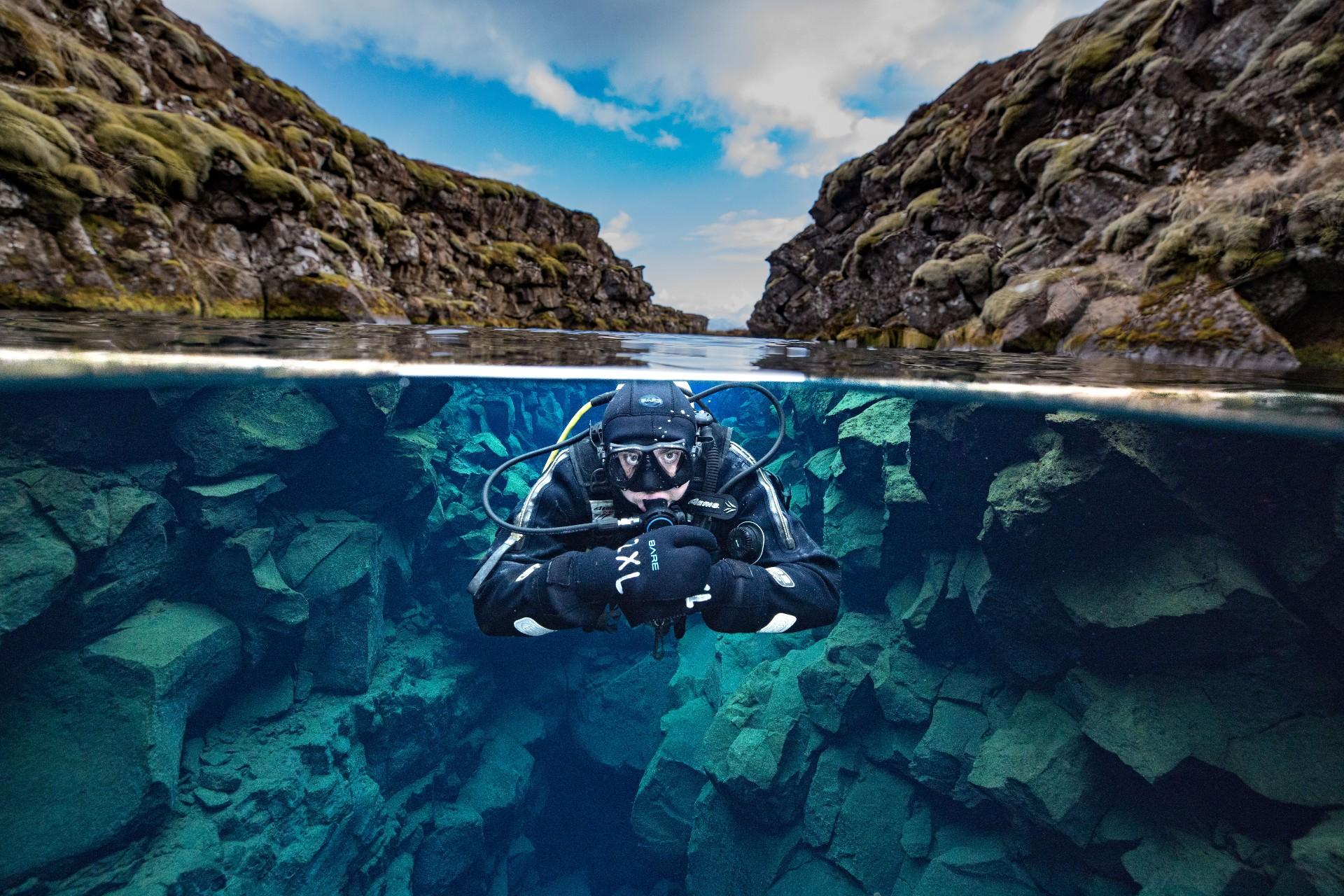 a scuba diver is swimming in a cave in the ocean .