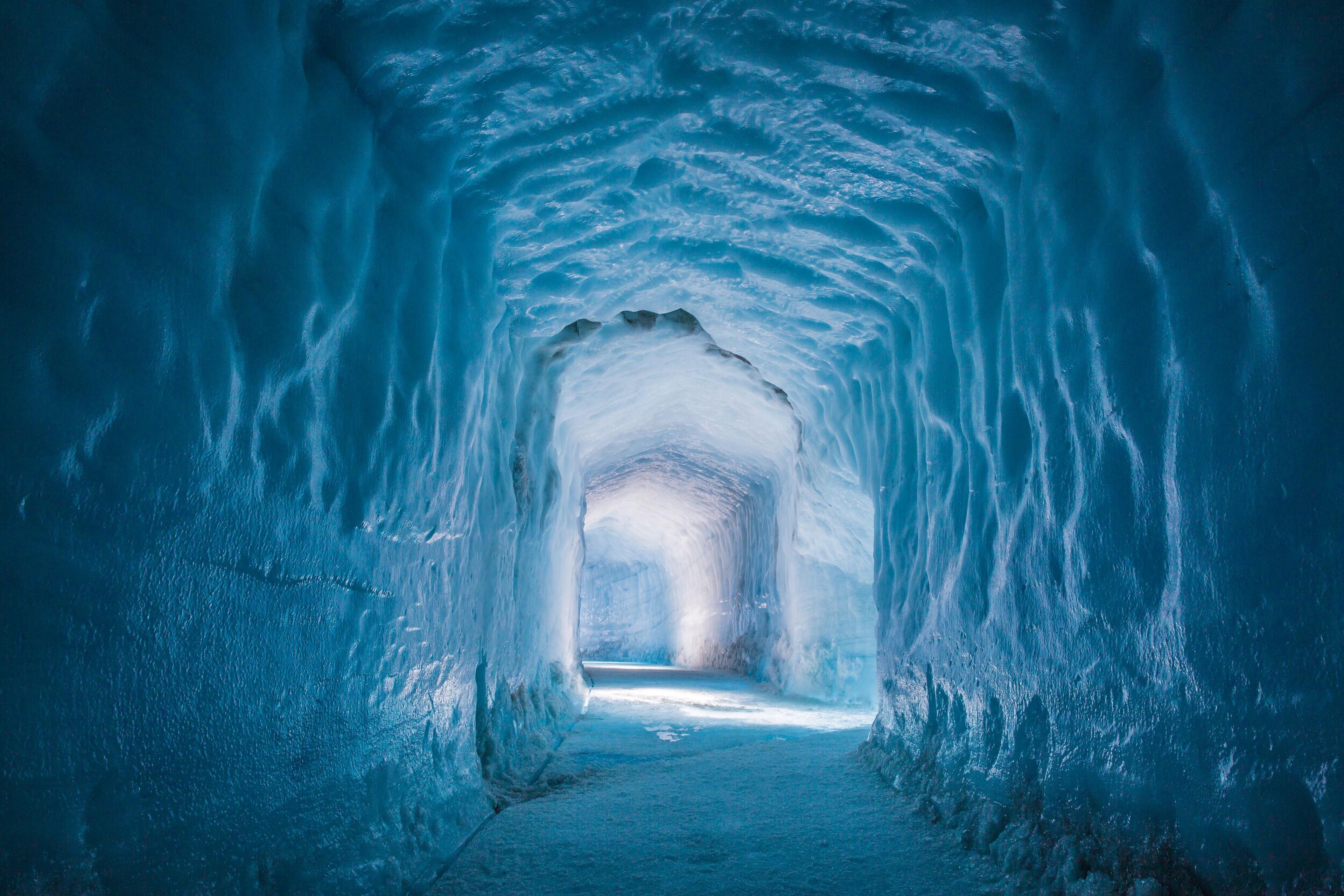 A stunning view of the illuminated blue ice walls and textured ceiling inside a tunnel of the Langjökull ice cave.