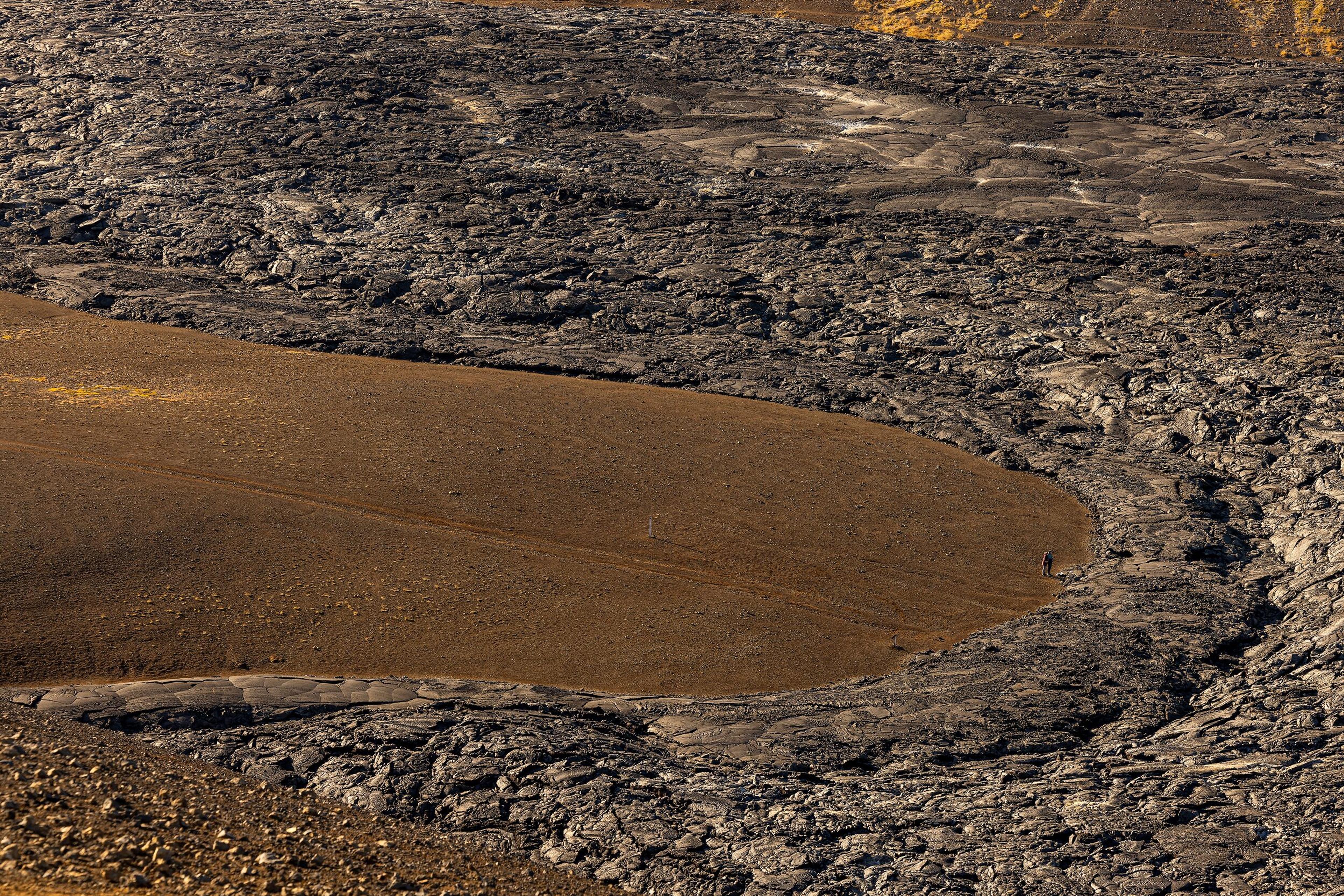  Aerial image of the Reykjanes eruption hiking trail showcasing the contrast between the rough volcanic landscape and the smooth brown hiking path.