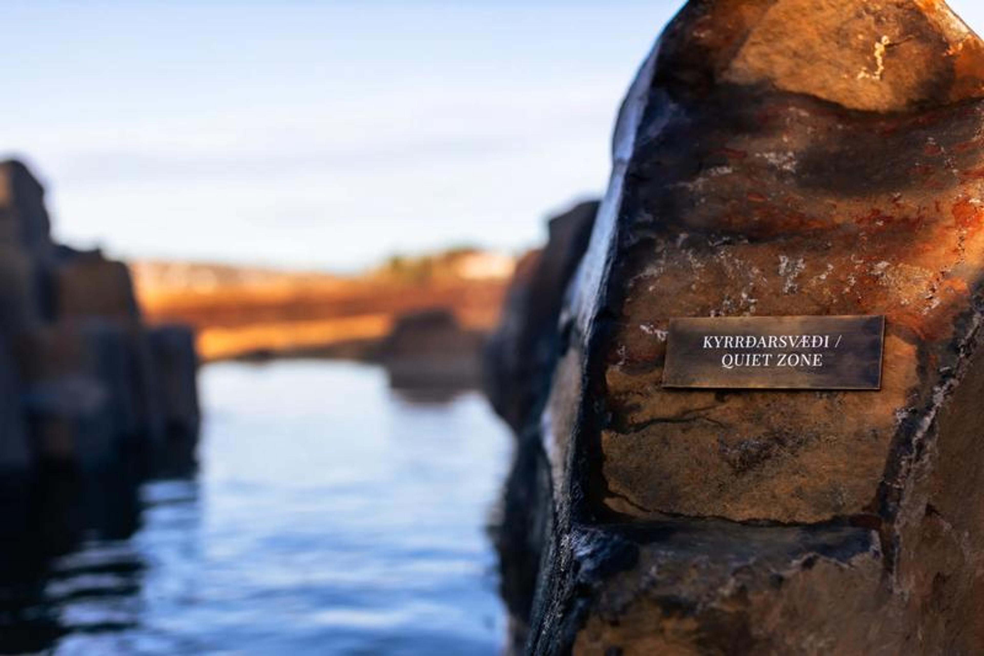 A rock with a "Quiet Zone" sign next to a blue lagoon.