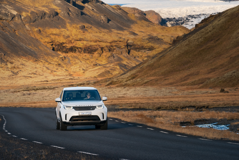 a white land rover is driving down a road