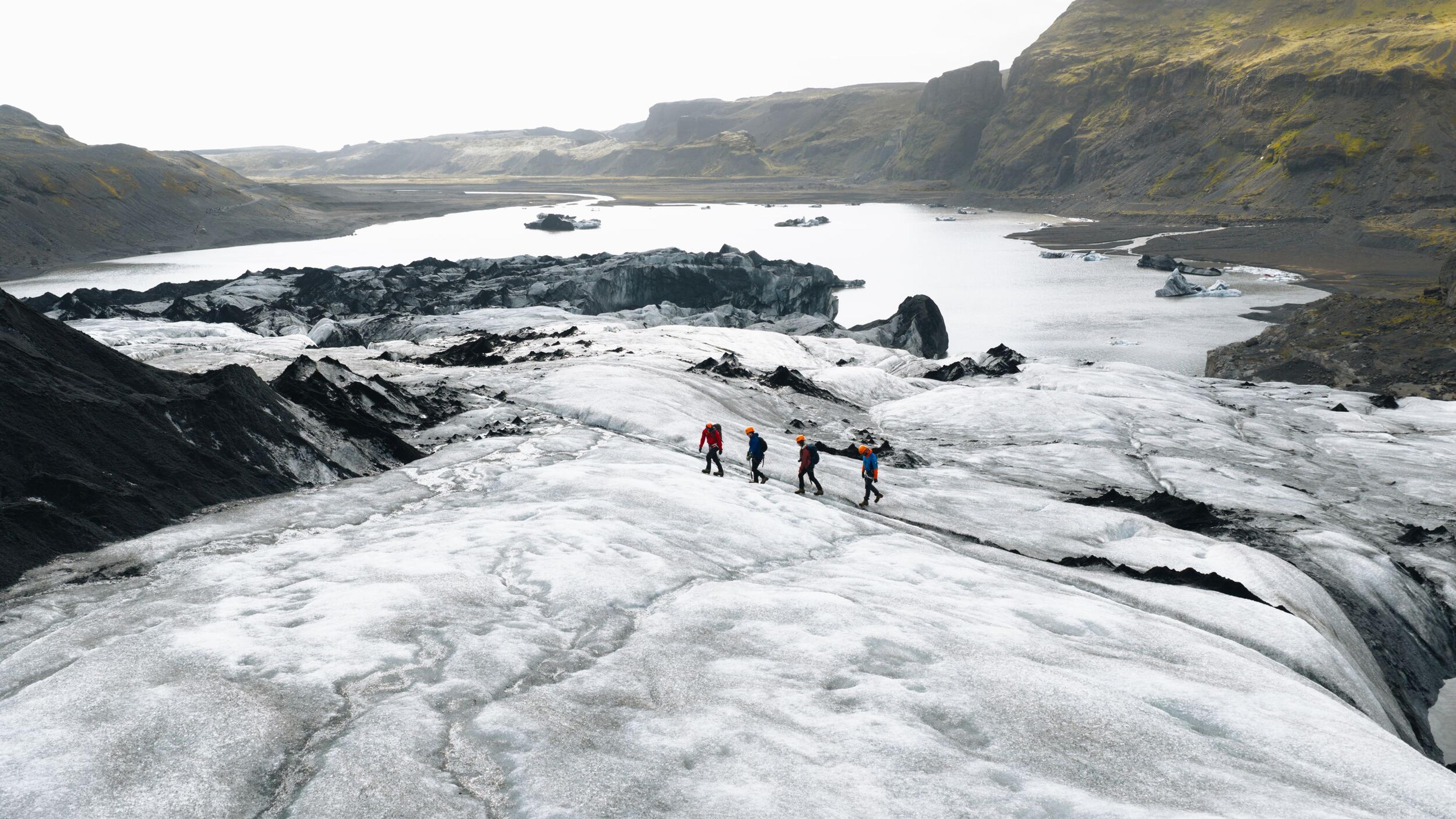a group of people are walking on top of a glacier .