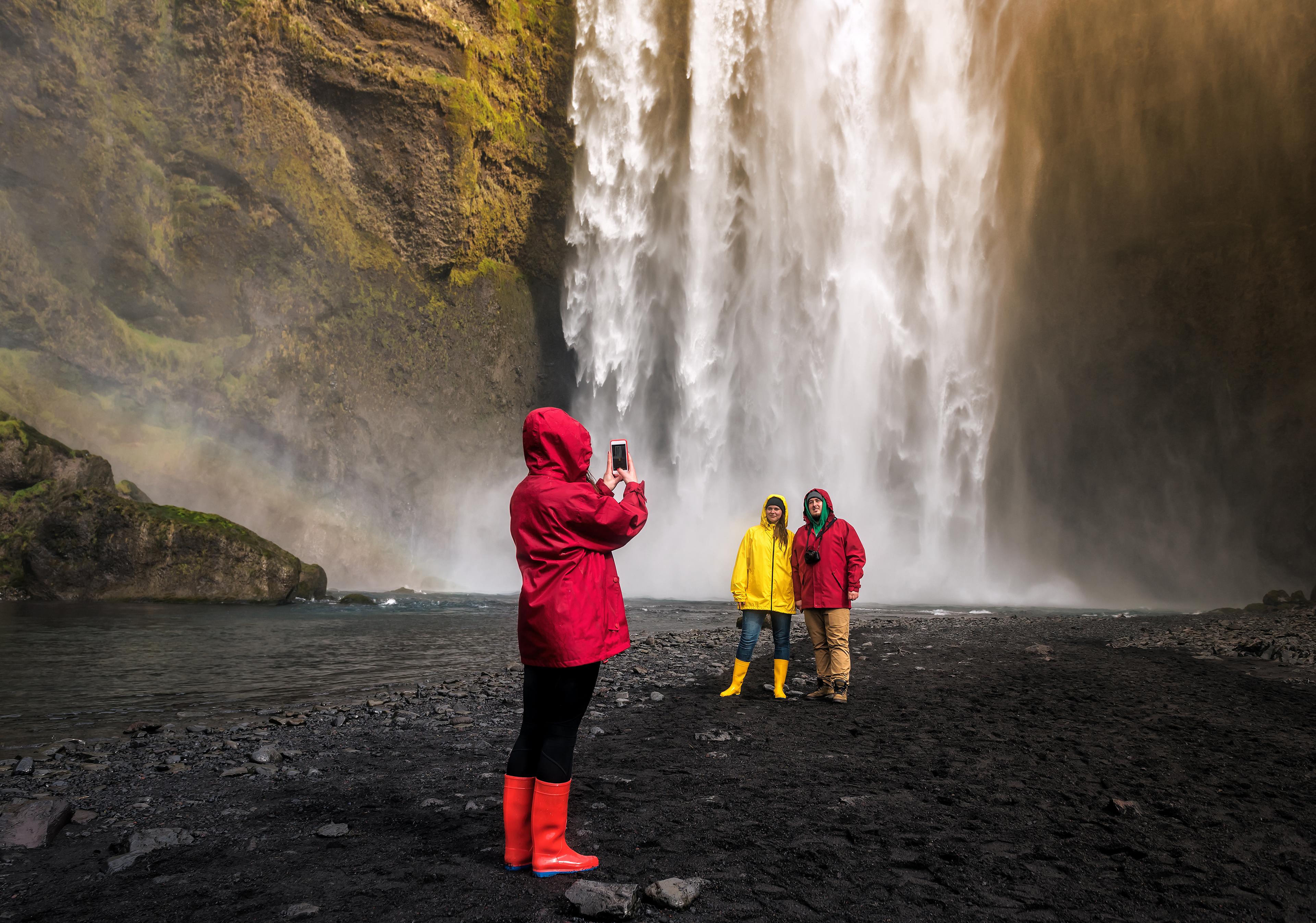 A group of tourists taking a picture in front of the Skogafoss Waterfall