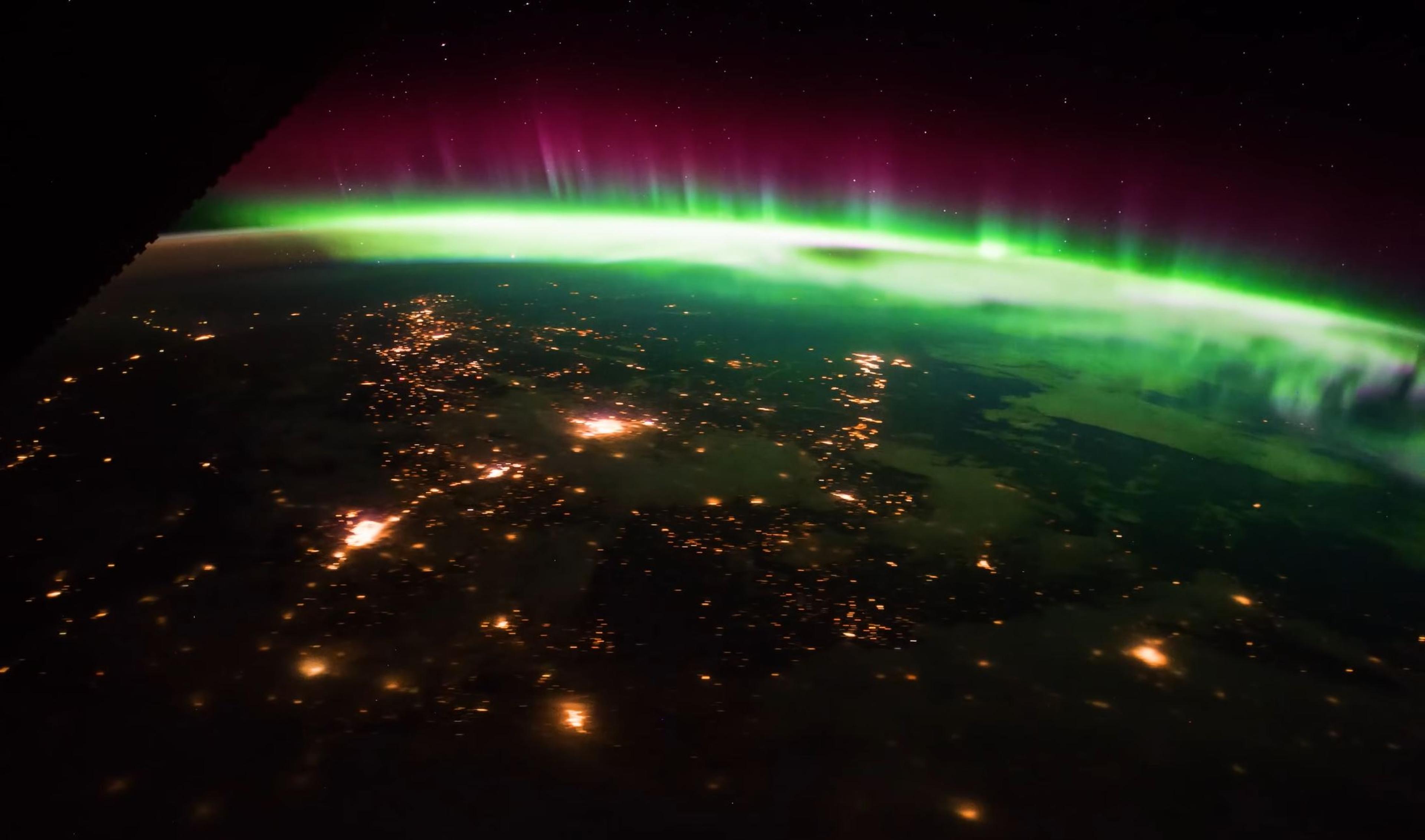 iew of the Northern Lights from space, with vibrant green and pink auroras over Earth