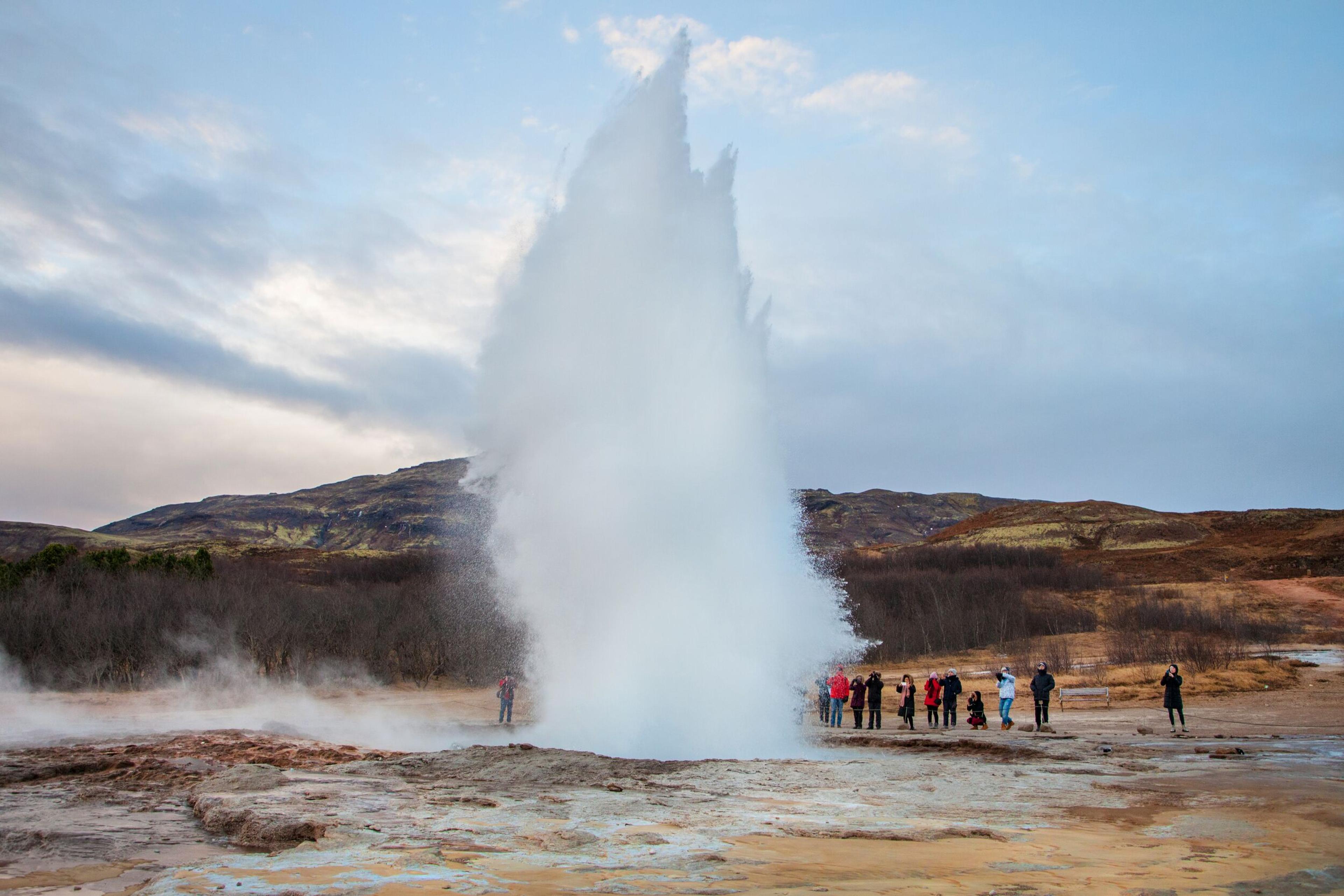 Geysir hotspring erupting in front of a group of tourists