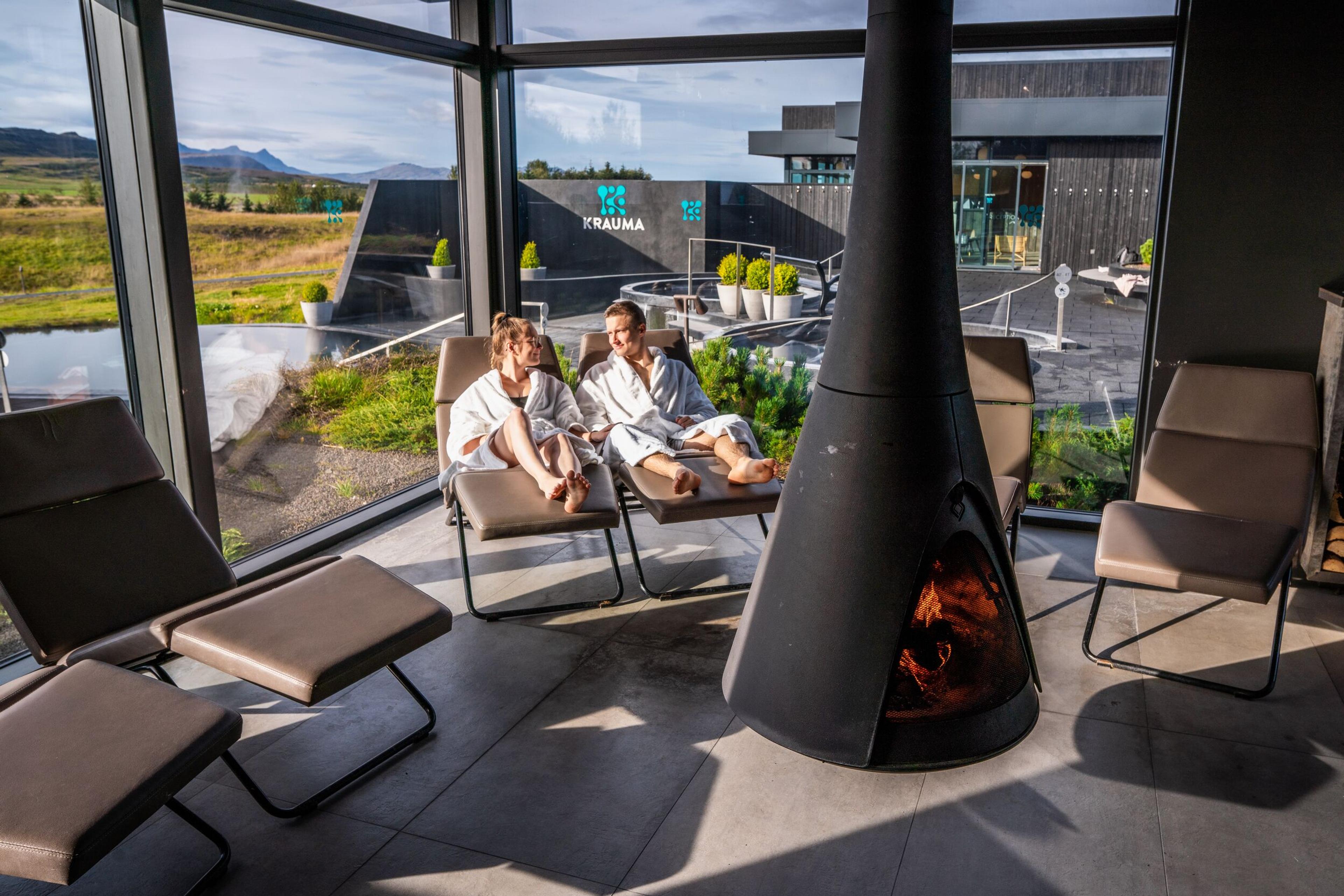a couple of people are sitting in chairs in front of a fireplace .