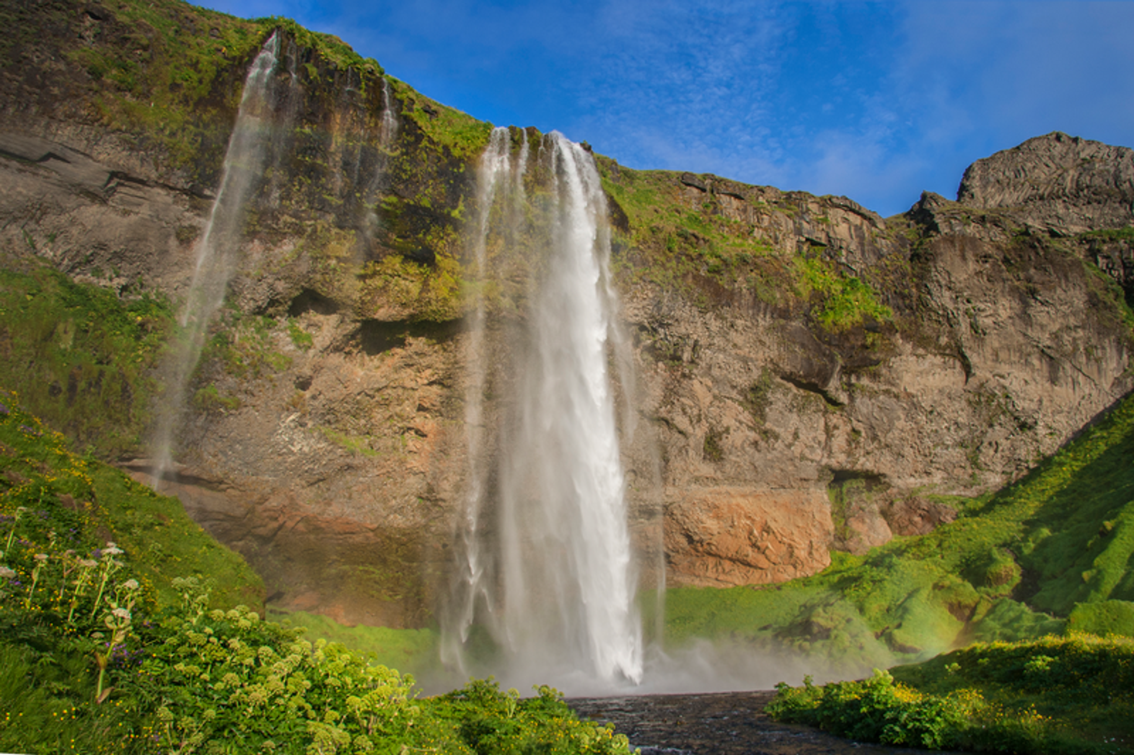 a waterfall in the middle of a green hillside