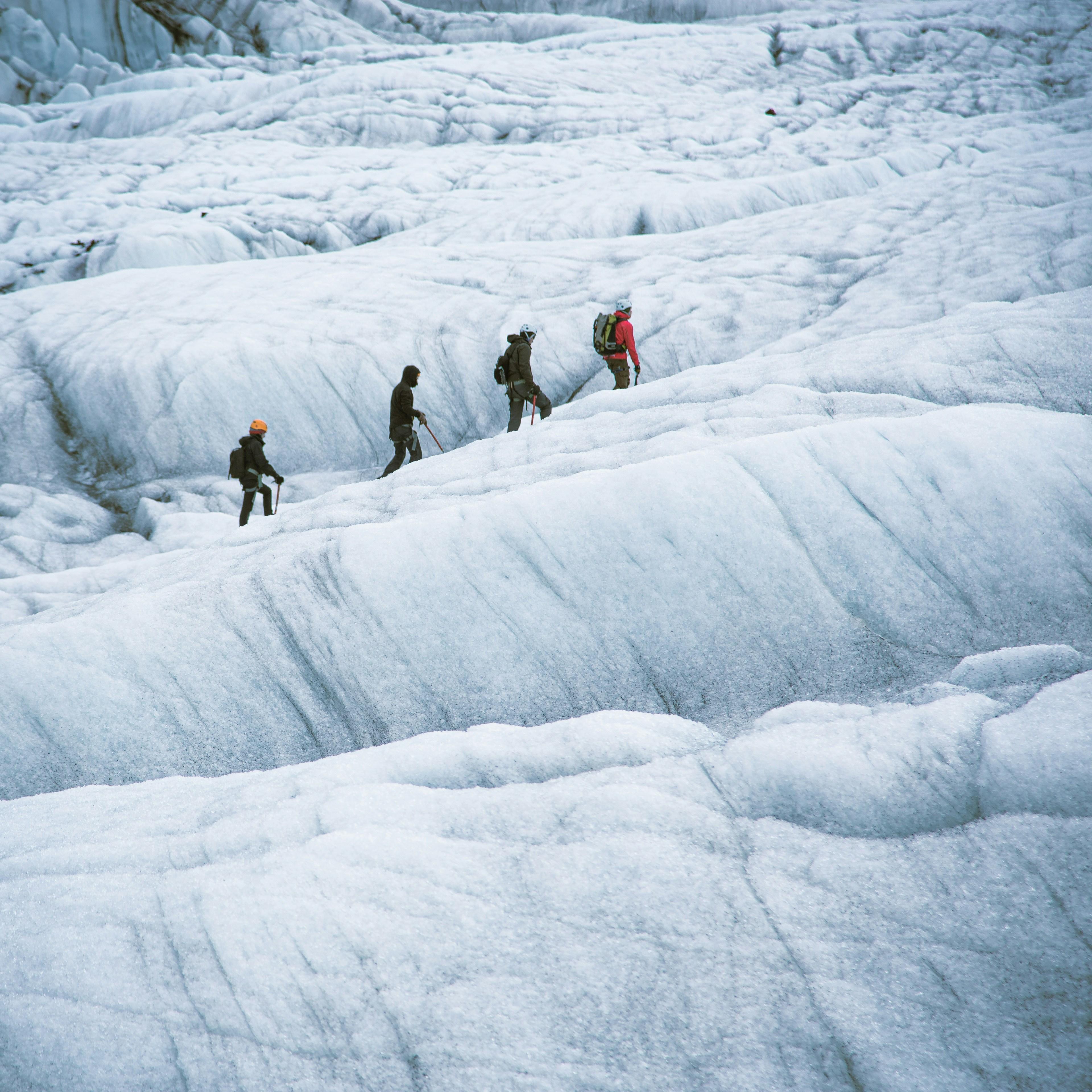 Group of hikers trekking across a vast glacier, equipped with gear, showcasing the adventure of ice hiking in Iceland.