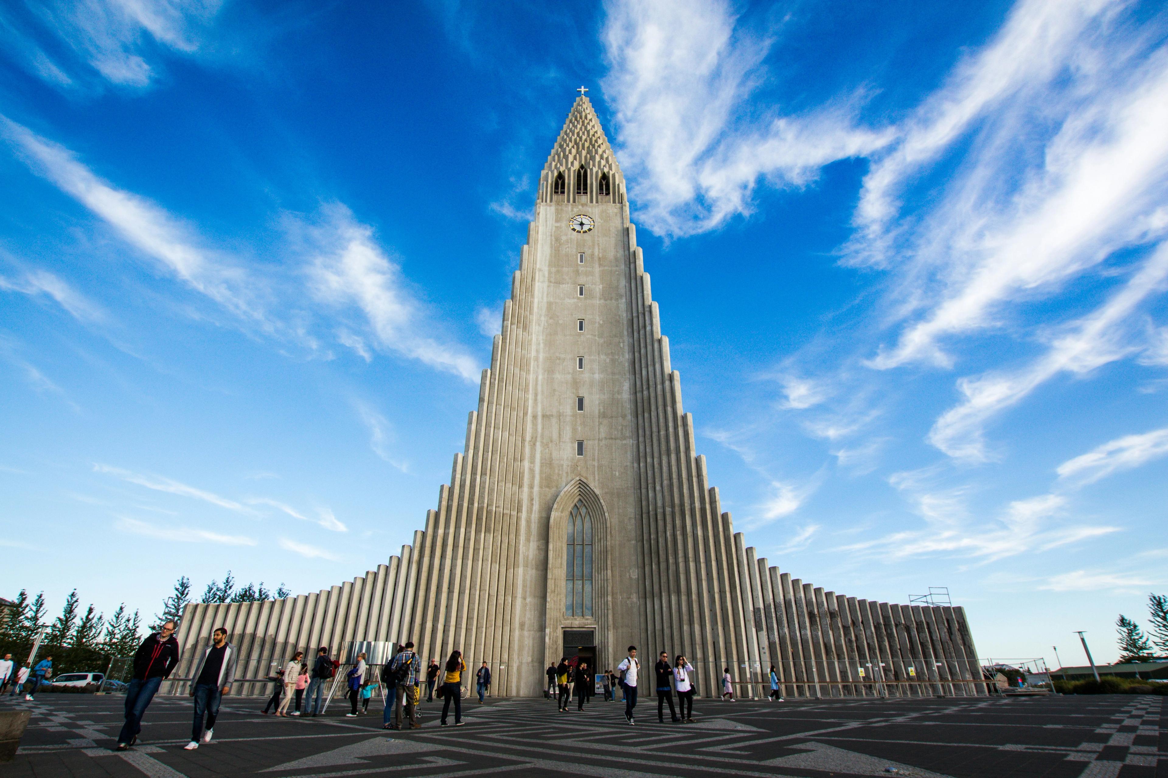 a group of people are standing in front of a large building with a clock tower .