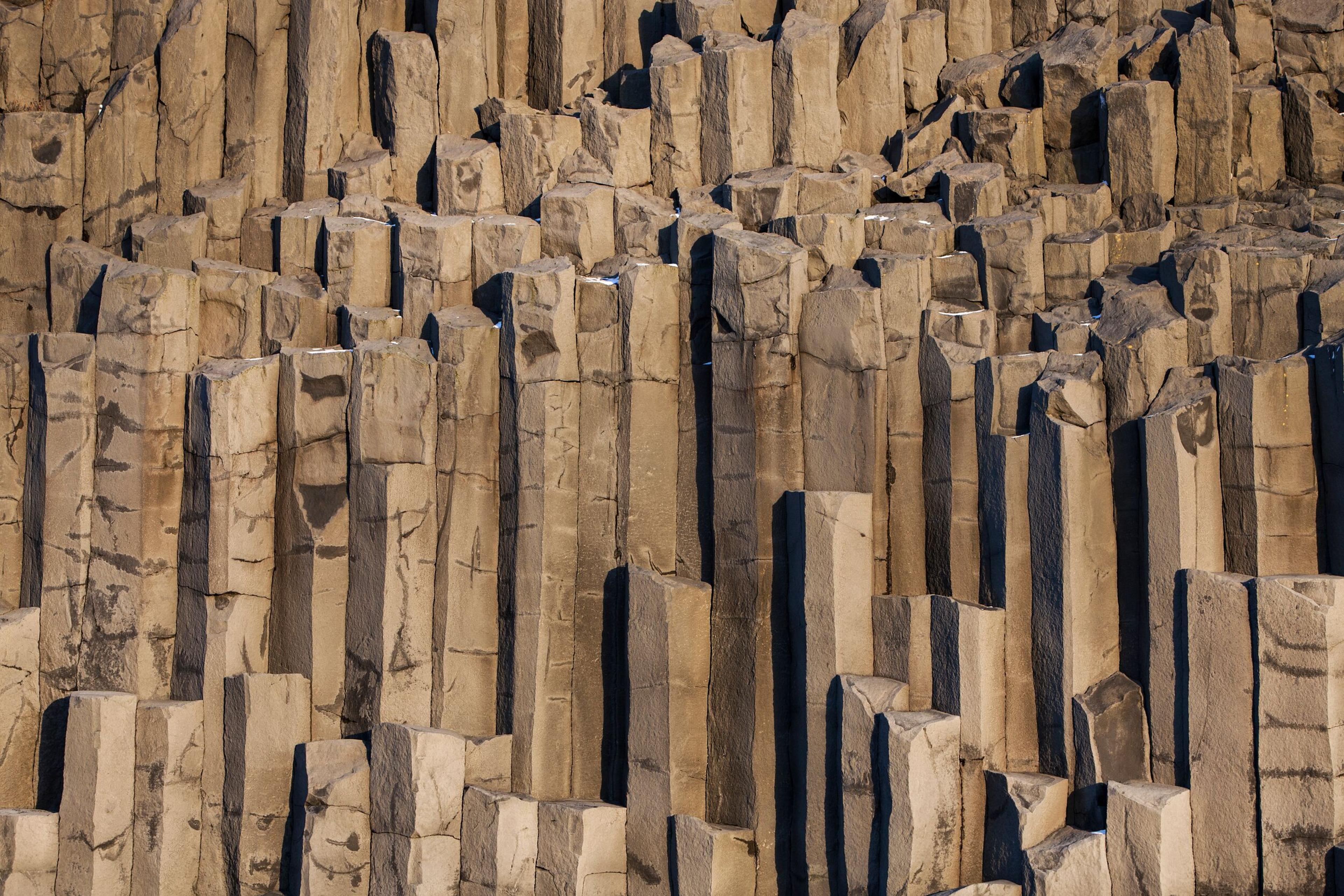  Close-up of the towering basalt columns at Reynisfjara beach, a geological marvel on Iceland's South Coast tour.