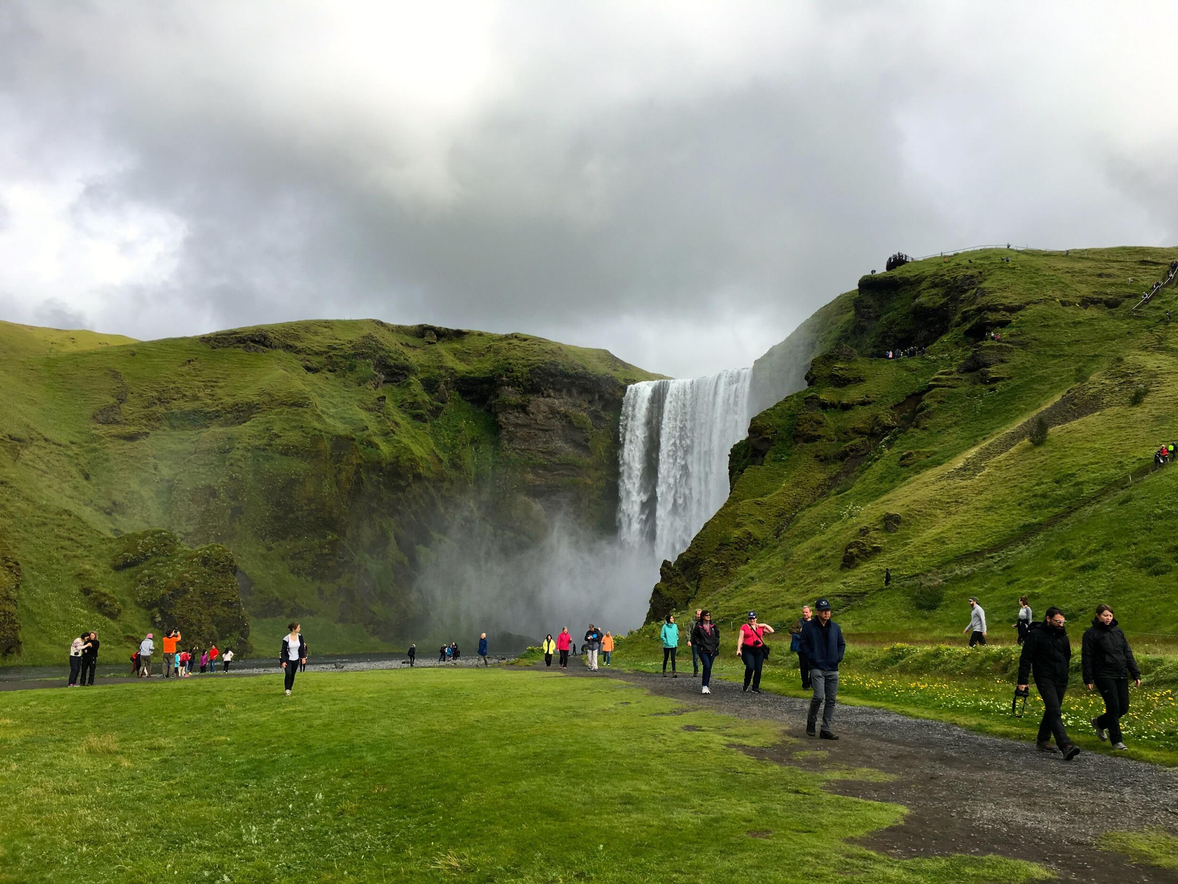 Tourists walking towards Skógafoss waterfall on the south coast of Iceland.