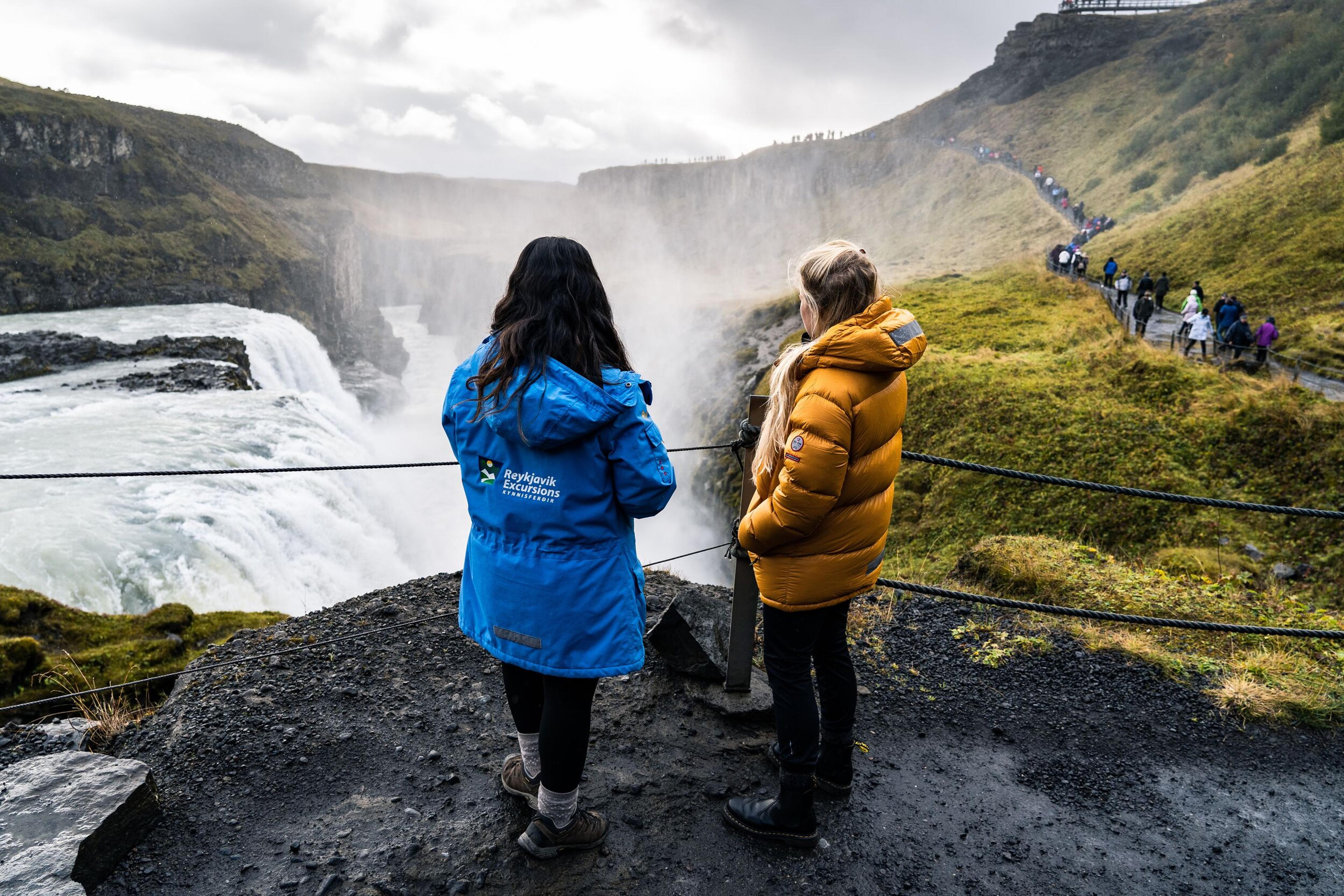 Two women lookng over the Gullfoss Waterfall. 