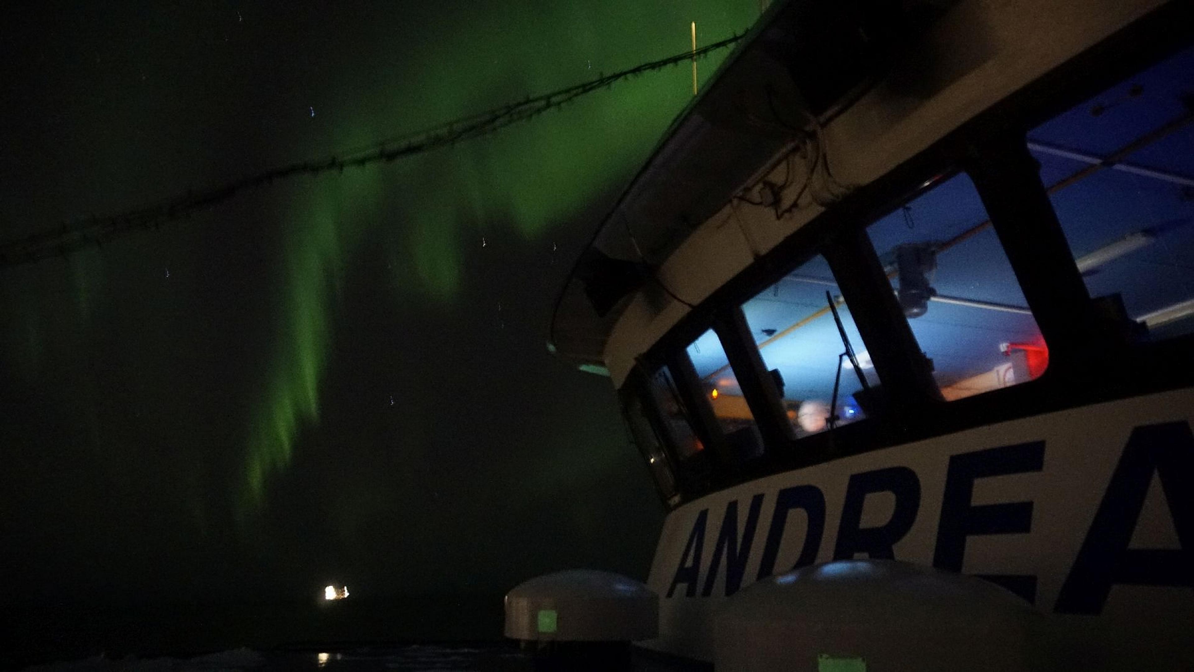 A boat named Andrea under green Northern Lights.